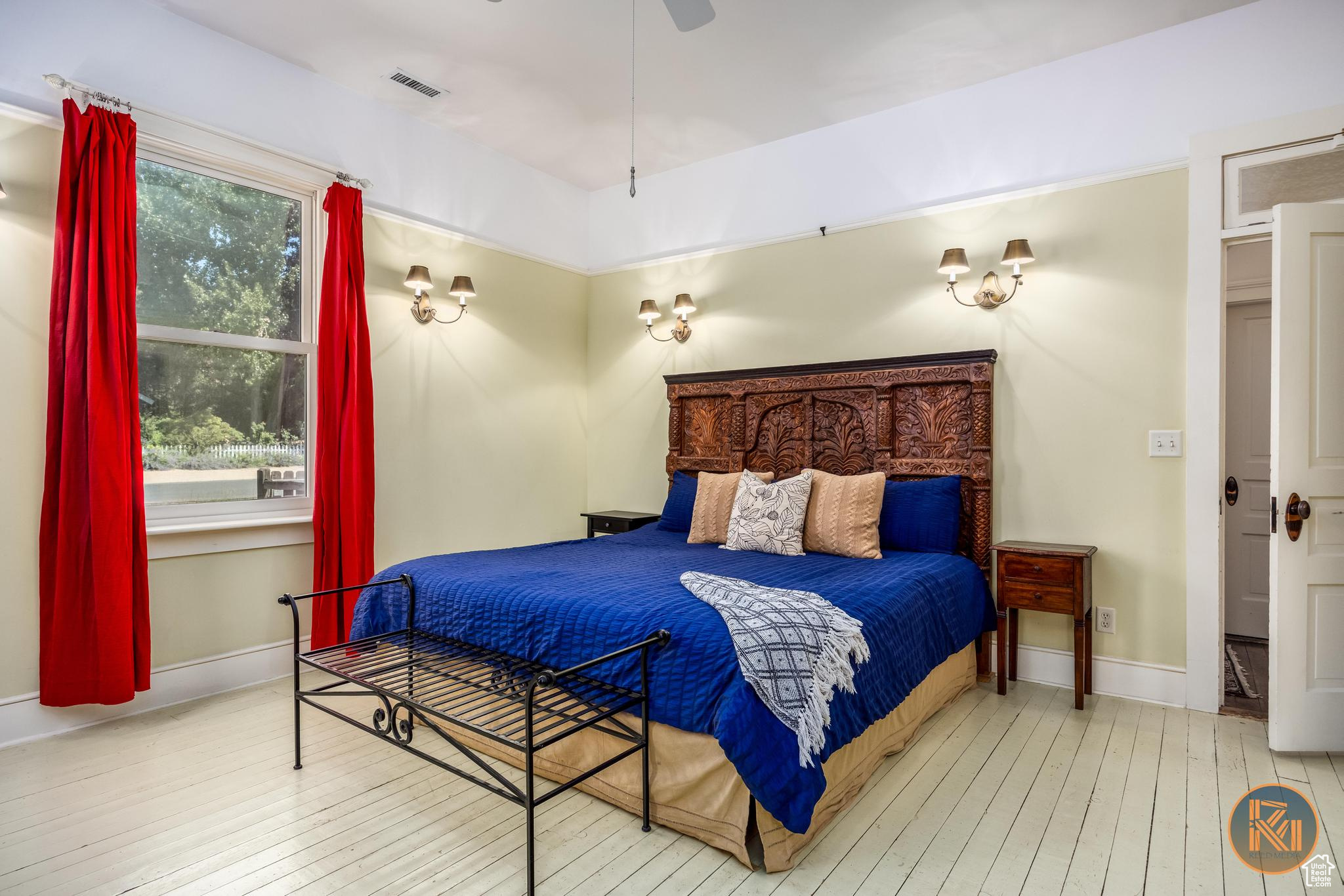 Bedroom with wood-type flooring, visible vents, and baseboards
