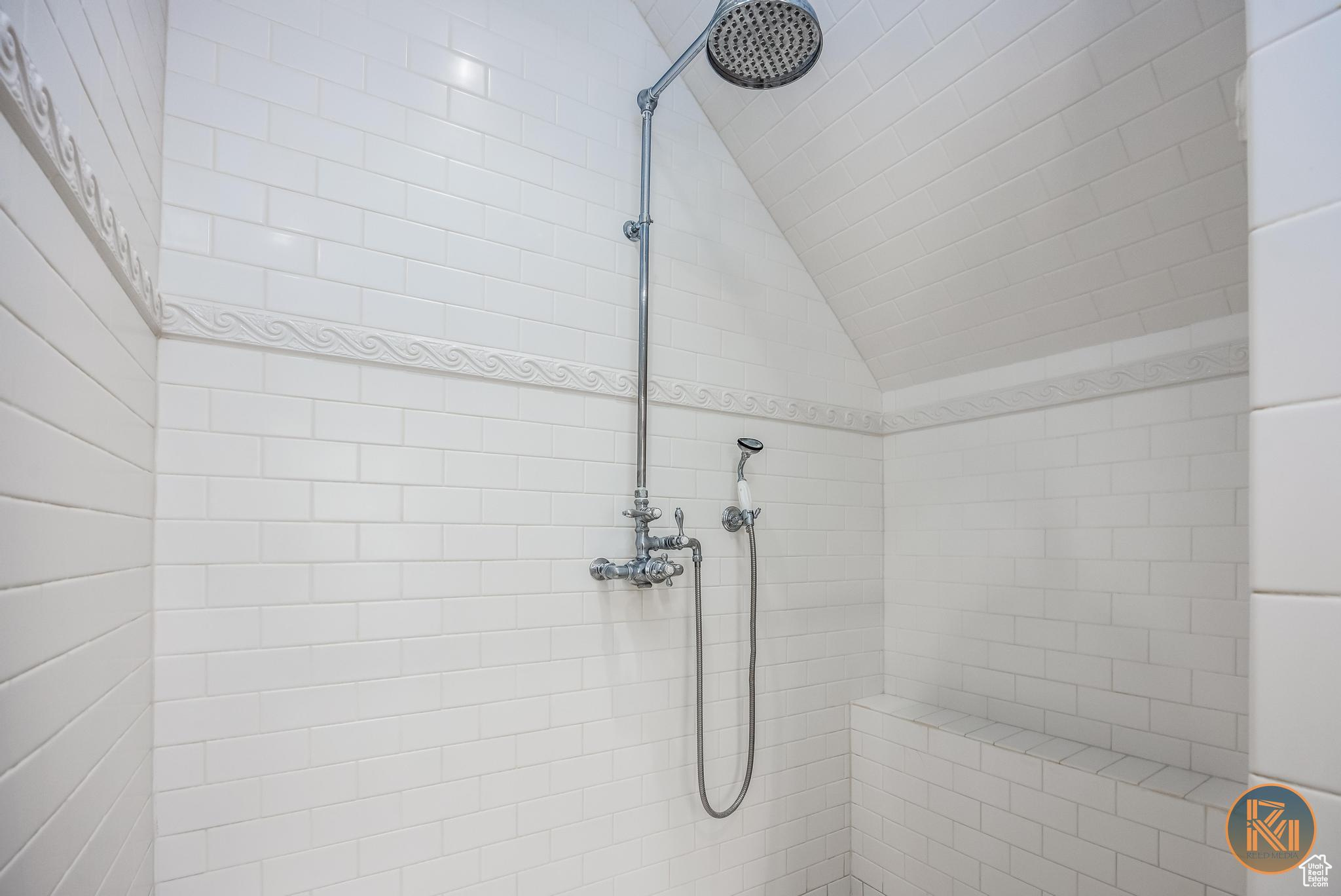 Full bathroom with vaulted ceiling and tiled shower