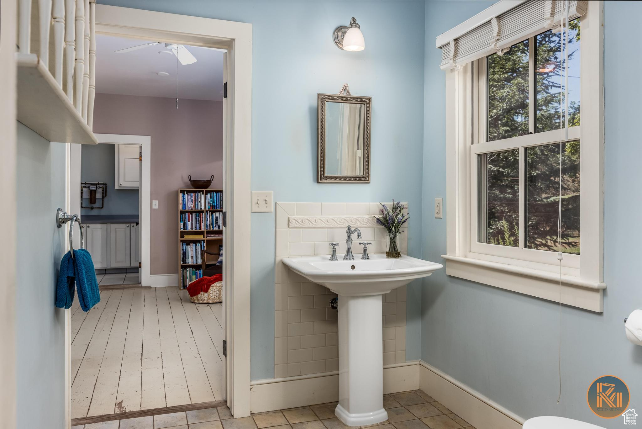 Bathroom with tile patterned floors, a sink, tile walls, and a ceiling fan