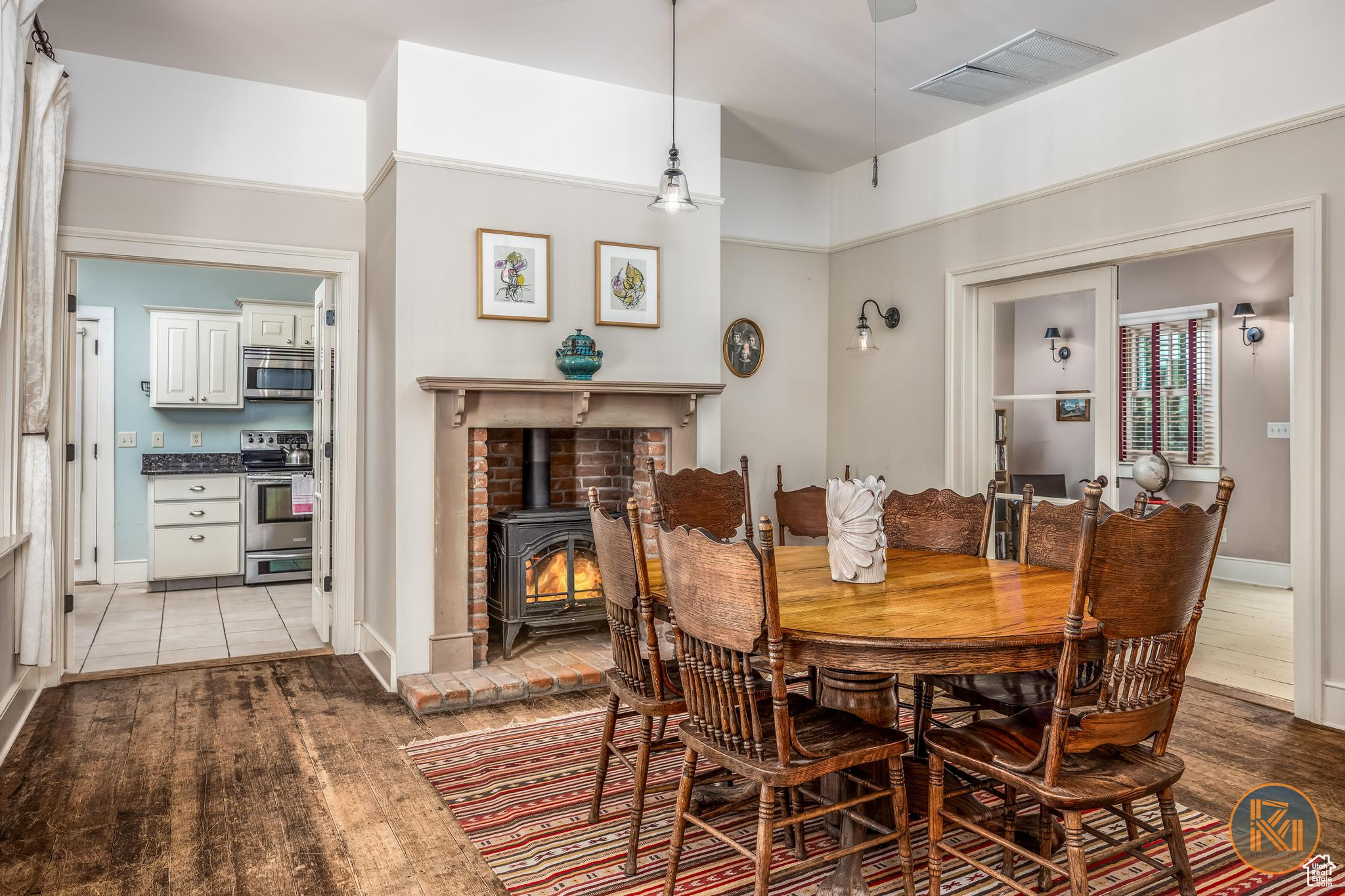 Dining area featuring a wood stove, light wood-style flooring, visible vents, and baseboards