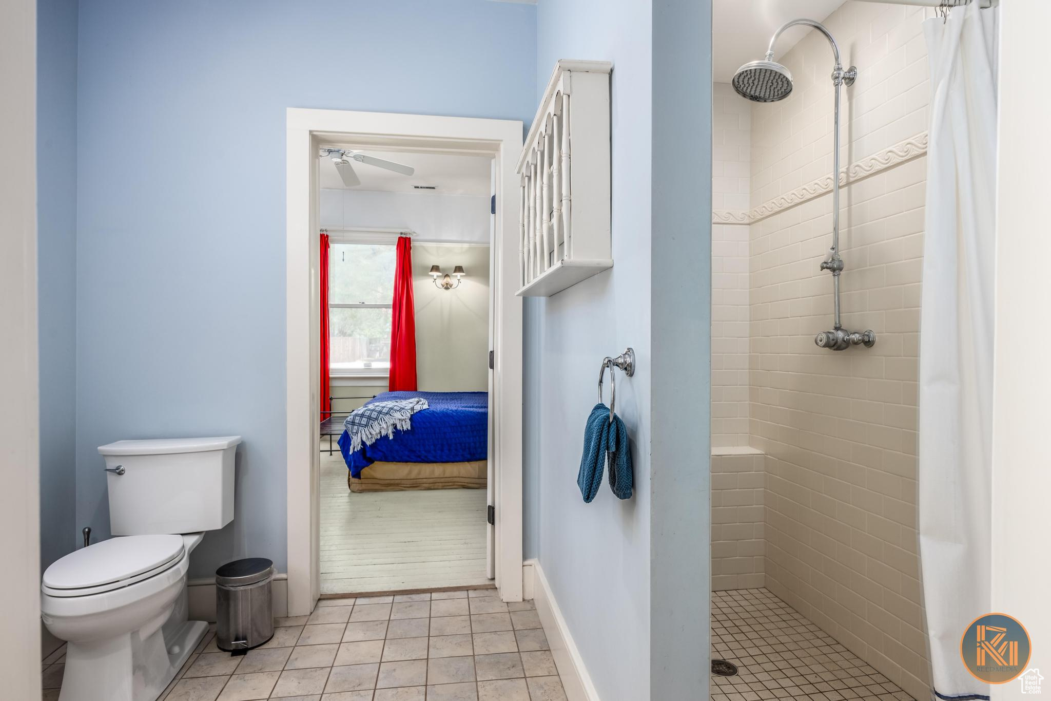 Bathroom with toilet, baseboards, a tile shower, and ensuite bath
