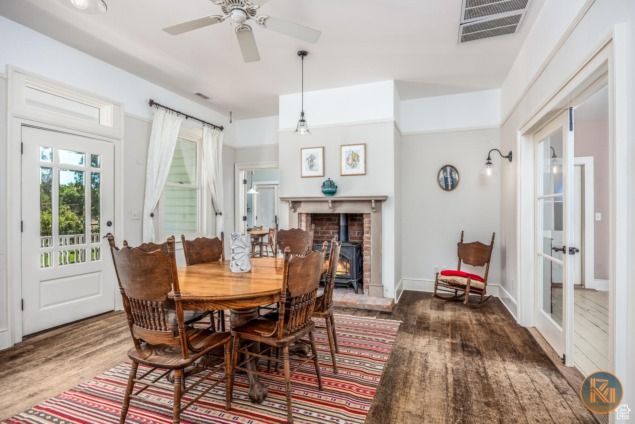 Dining room featuring french doors, visible vents, a ceiling fan, a wood stove, and wood finished floors