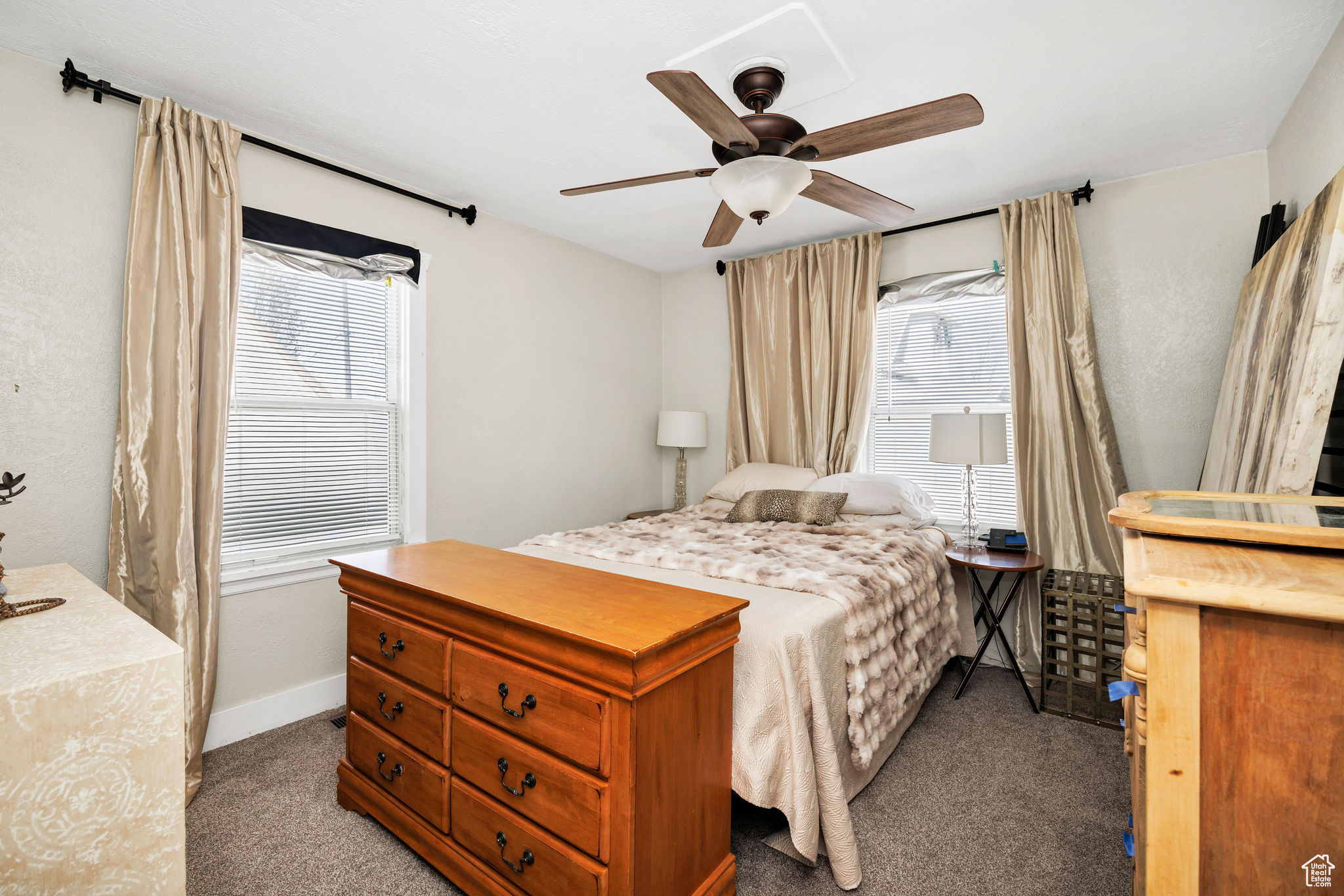 Carpeted bedroom with multiple windows, a ceiling fan, and baseboards