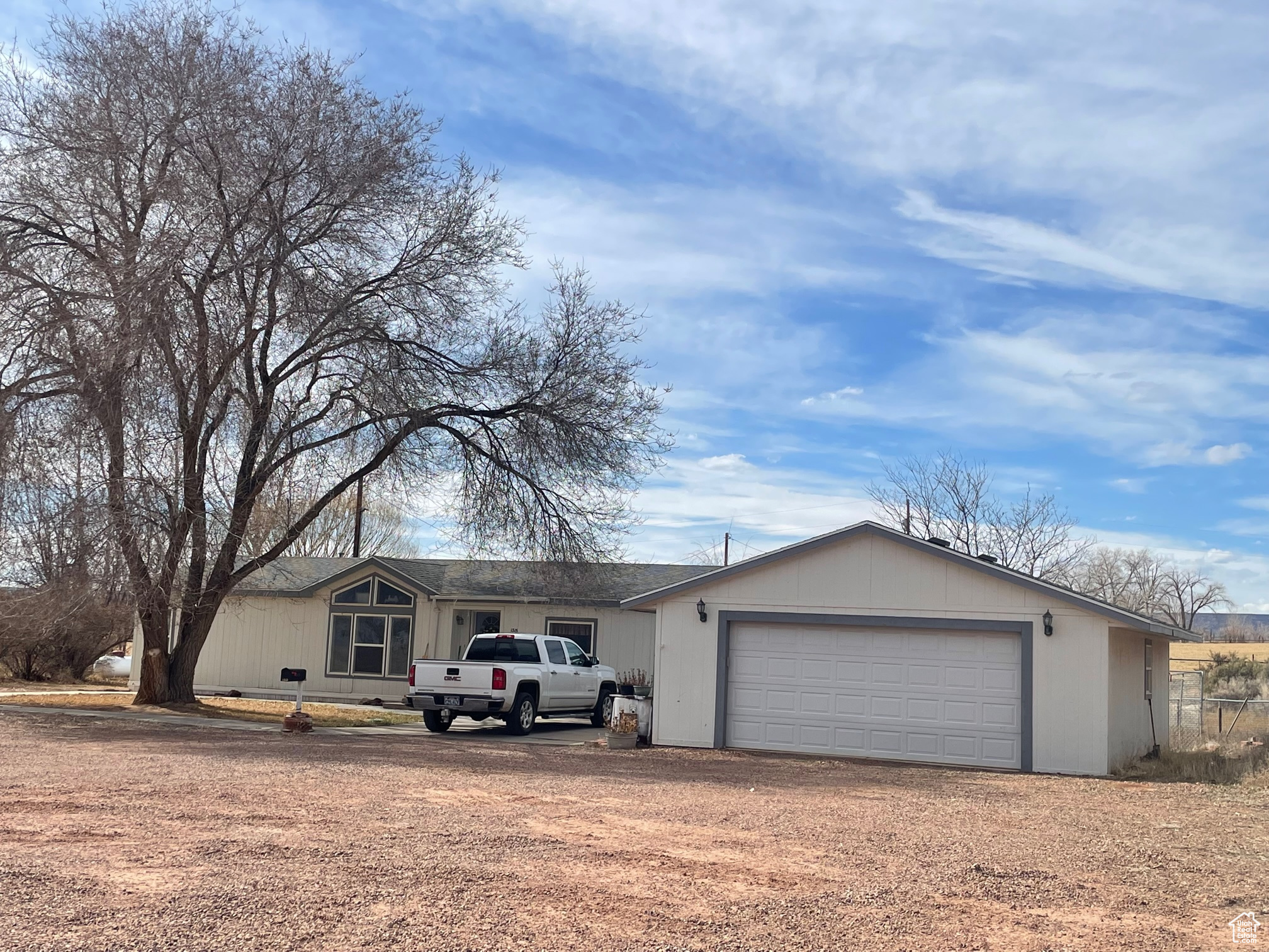 View of front of home featuring an attached garage and dirt driveway