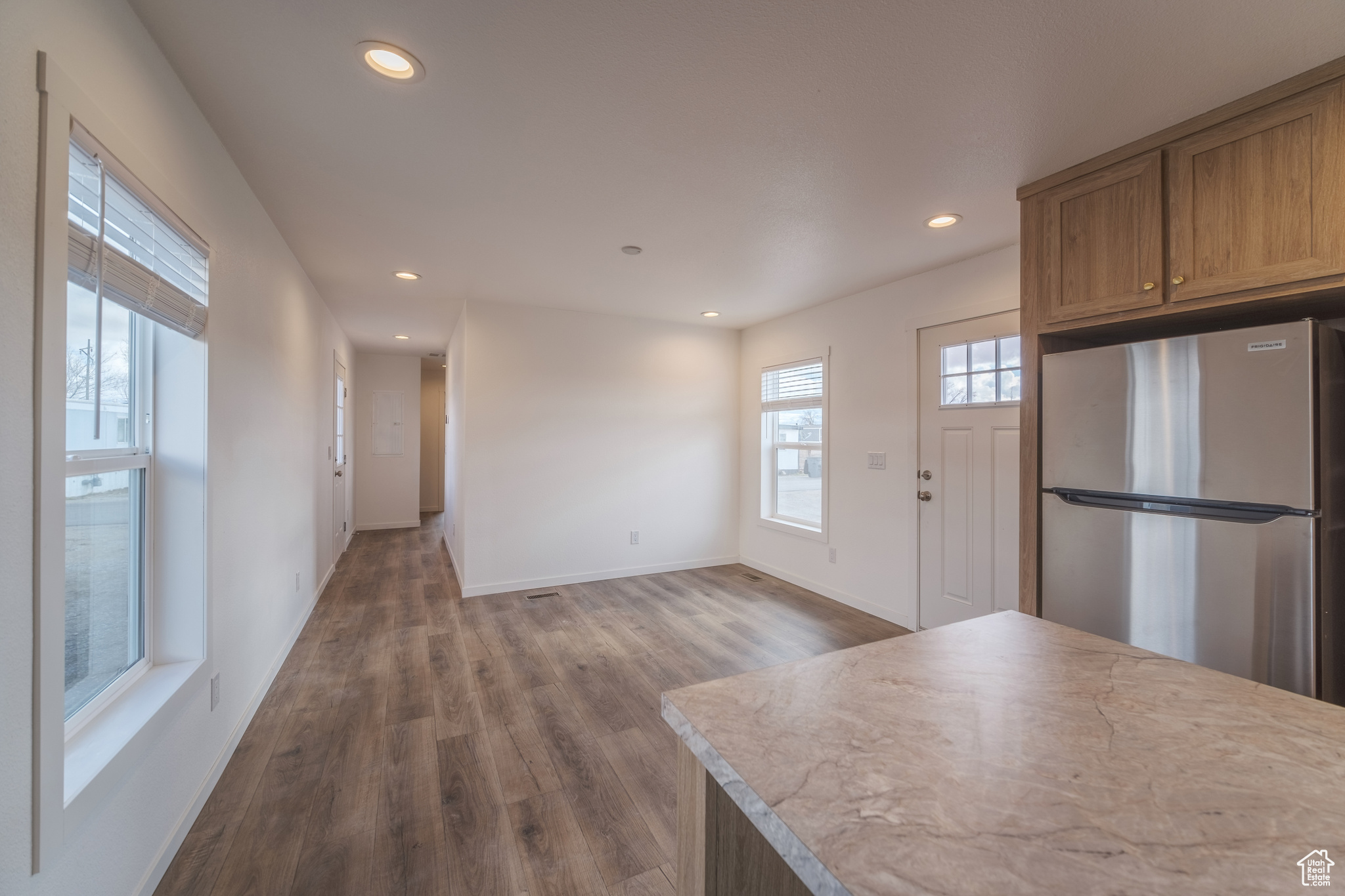 Kitchen featuring baseboards, recessed lighting, dark wood-style flooring, freestanding refrigerator, and light countertops