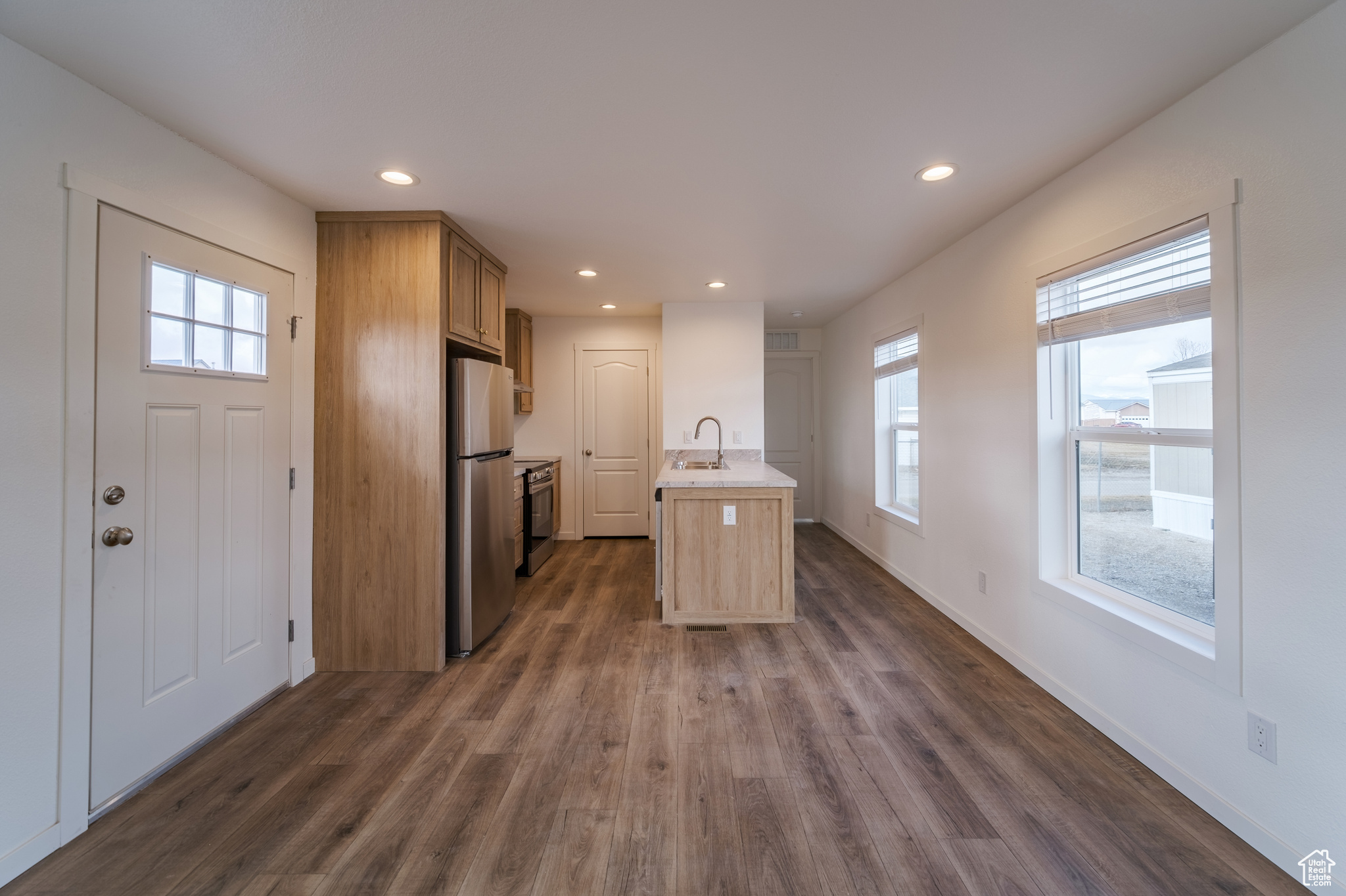 Kitchen with light countertops, recessed lighting, dark wood-style floors, stainless steel appliances, and a sink