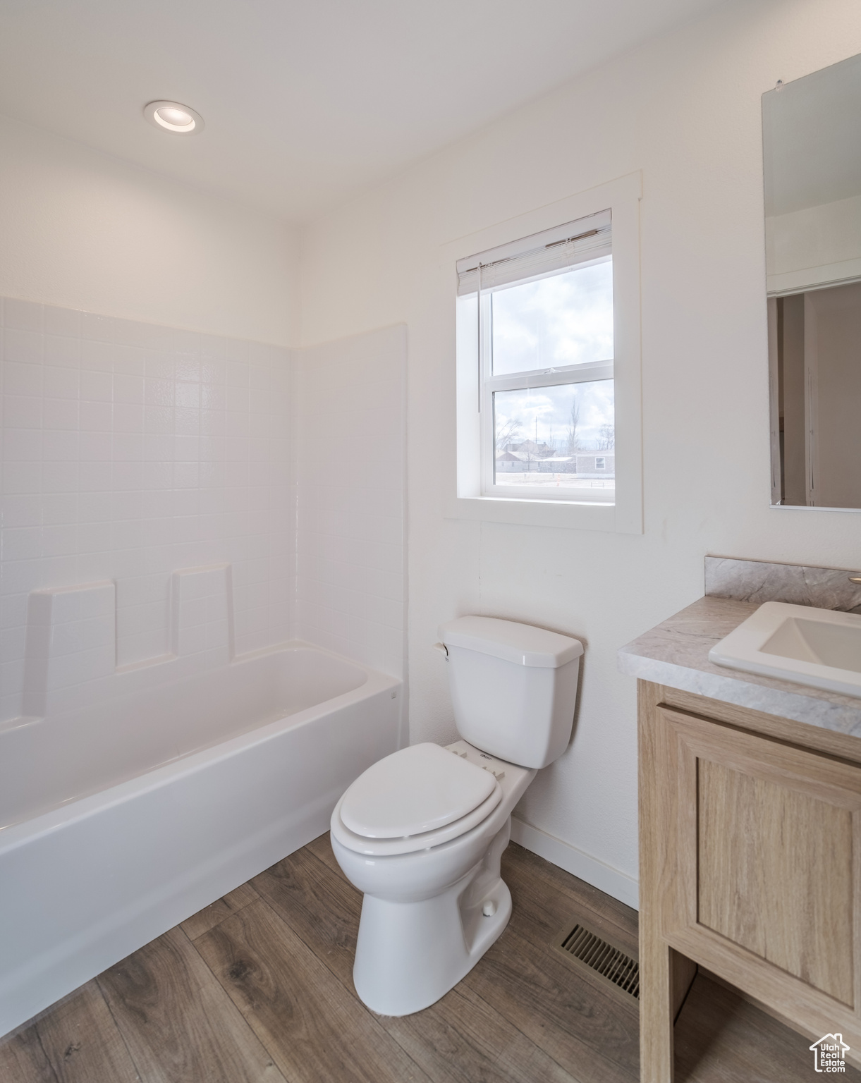 Full bathroom with visible vents, toilet, vanity, and wood finished floors