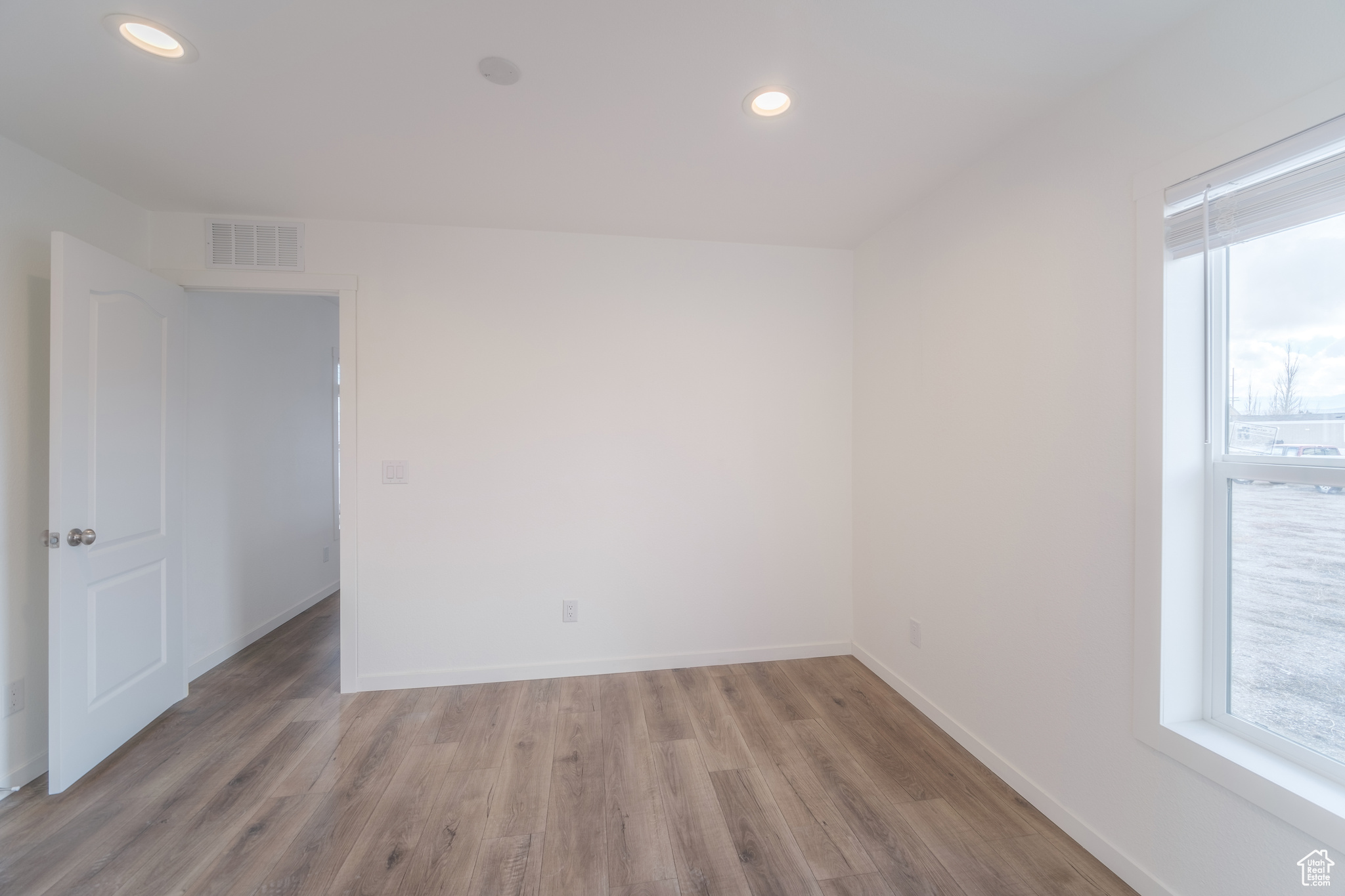 Spare room featuring light wood finished floors, visible vents, recessed lighting, and baseboards