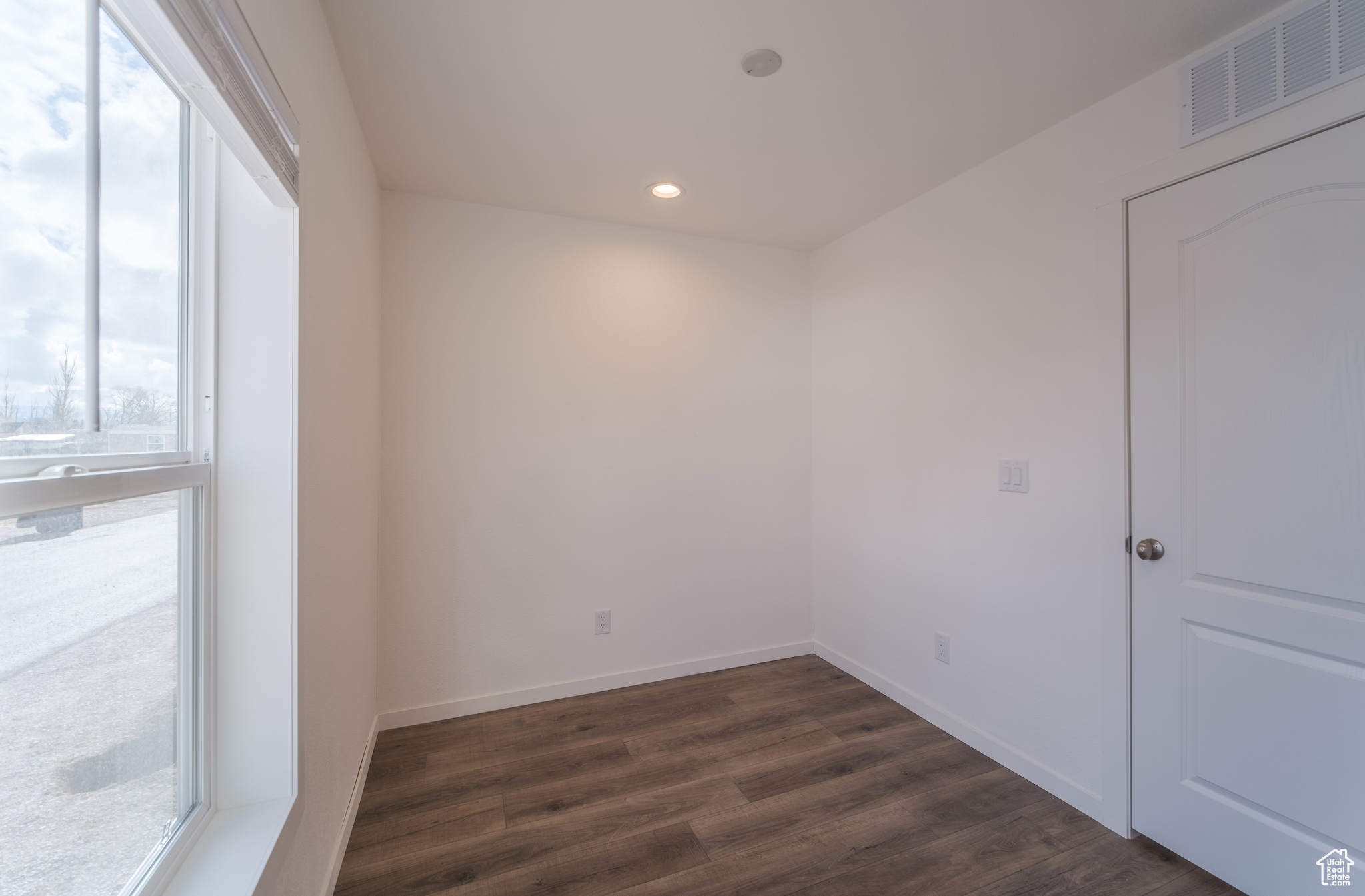 Empty room with visible vents, recessed lighting, dark wood-type flooring, and baseboards