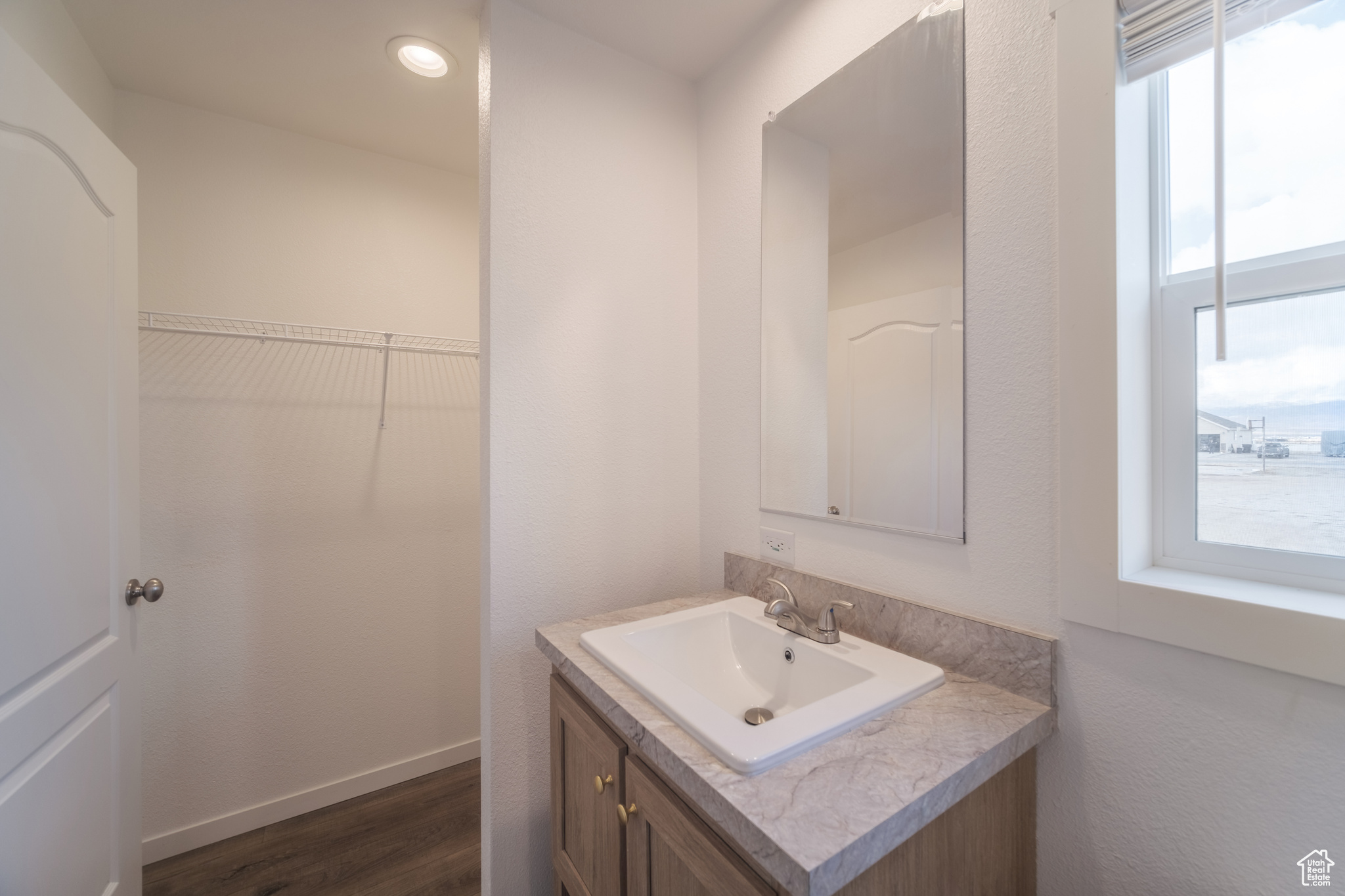 Bathroom with vanity, a walk in closet, wood finished floors, and baseboards