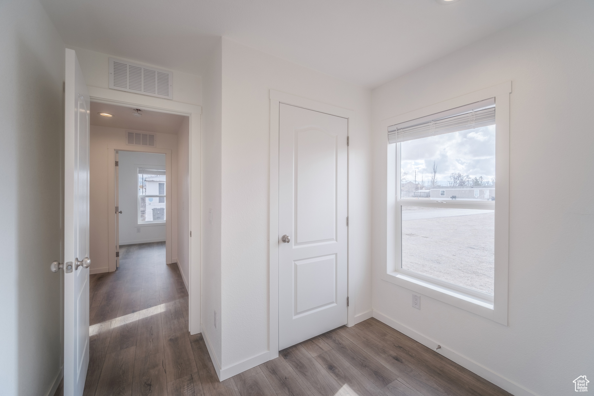 Hallway featuring visible vents, baseboards, and wood finished floors