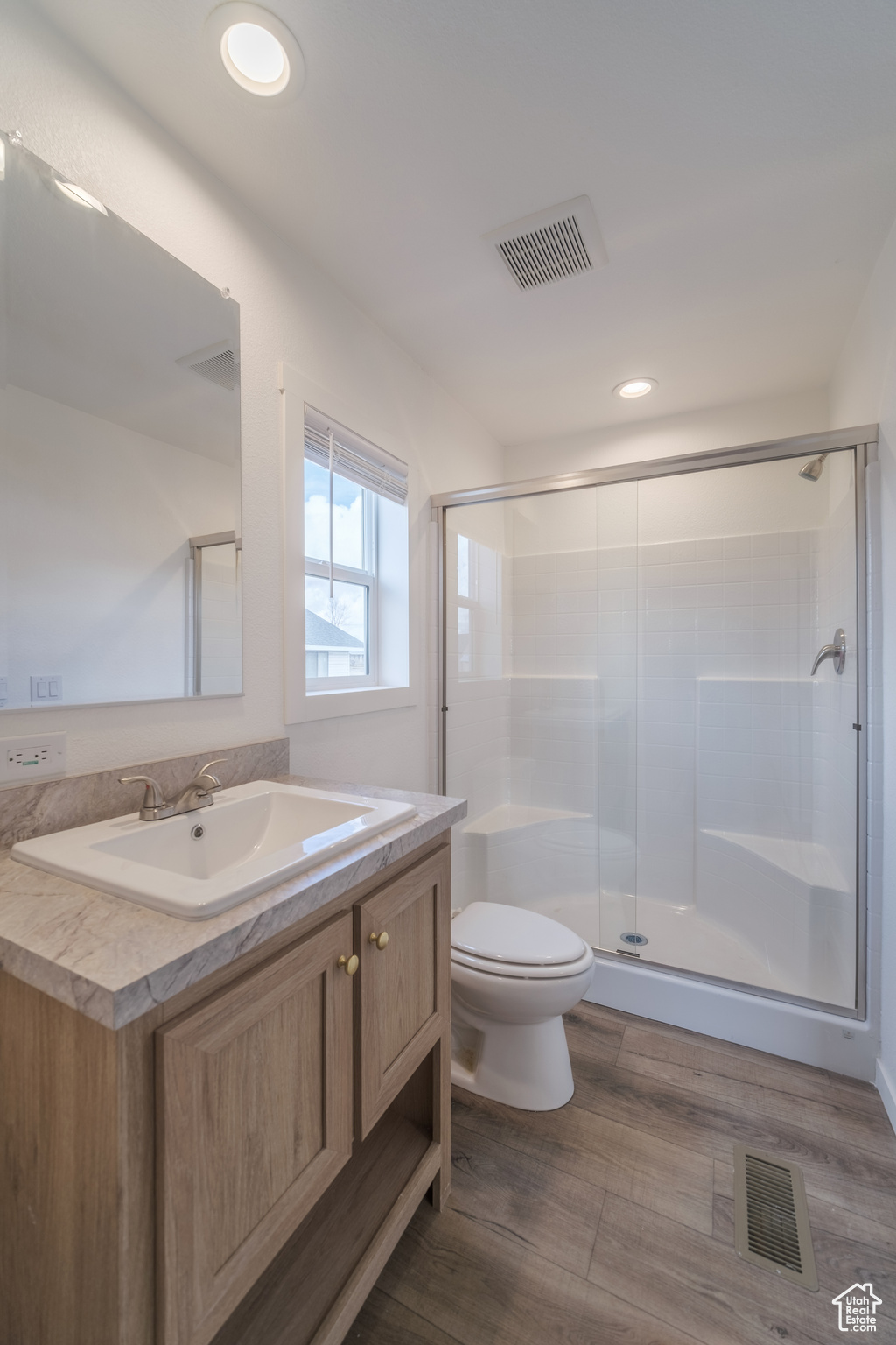 Full bathroom with vanity, a shower stall, toilet, and visible vents