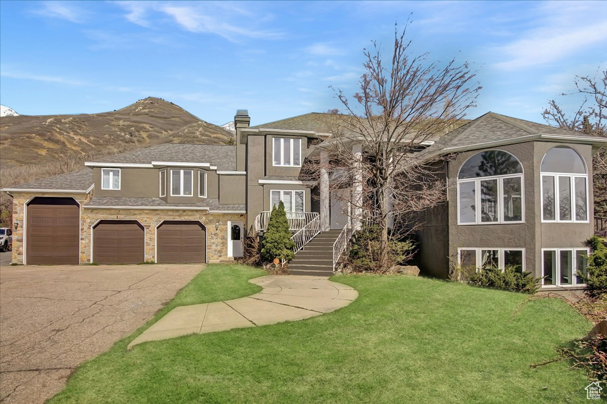 View of front of property featuring a front lawn, a chimney, driveway, and stucco siding