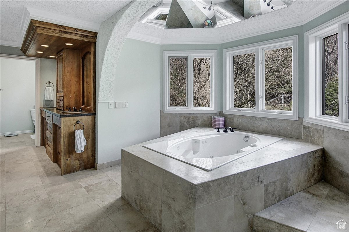 Full bathroom with vanity, a textured ceiling, a whirlpool tub, and crown molding