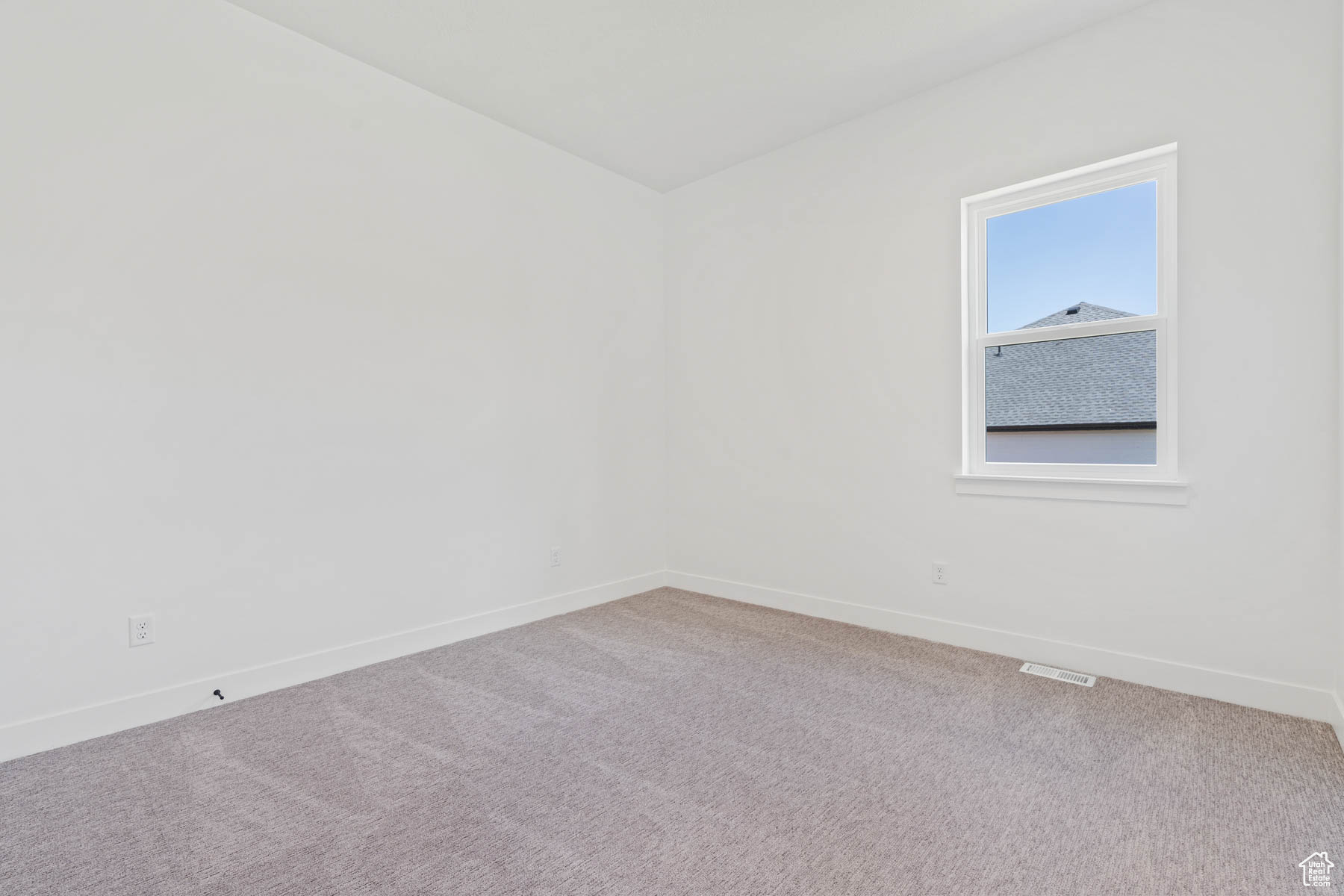 Carpeted spare room featuring visible vents and baseboards