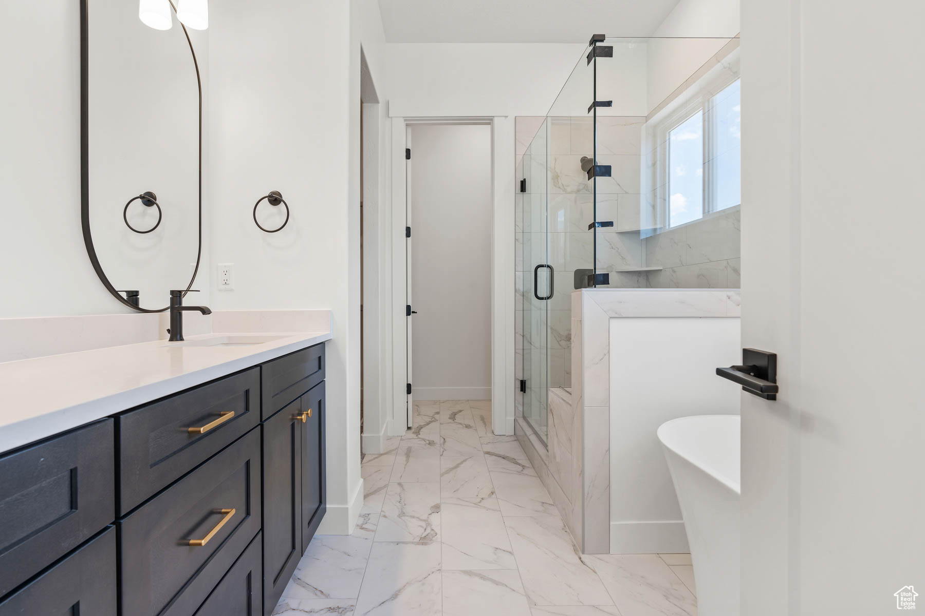 Full bathroom with vanity, baseboards, a freestanding bath, a shower stall, and marble finish floor