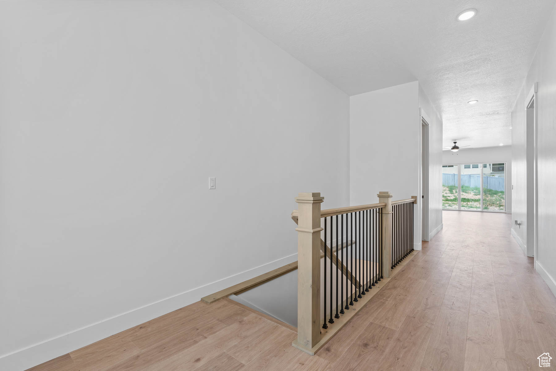 Corridor featuring an upstairs landing, light wood-type flooring, and baseboards