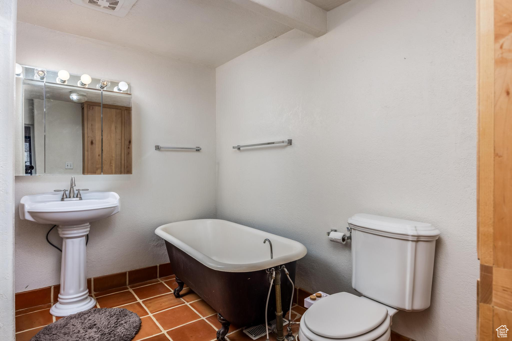 Full bathroom with a freestanding bath, toilet, and tile patterned flooring