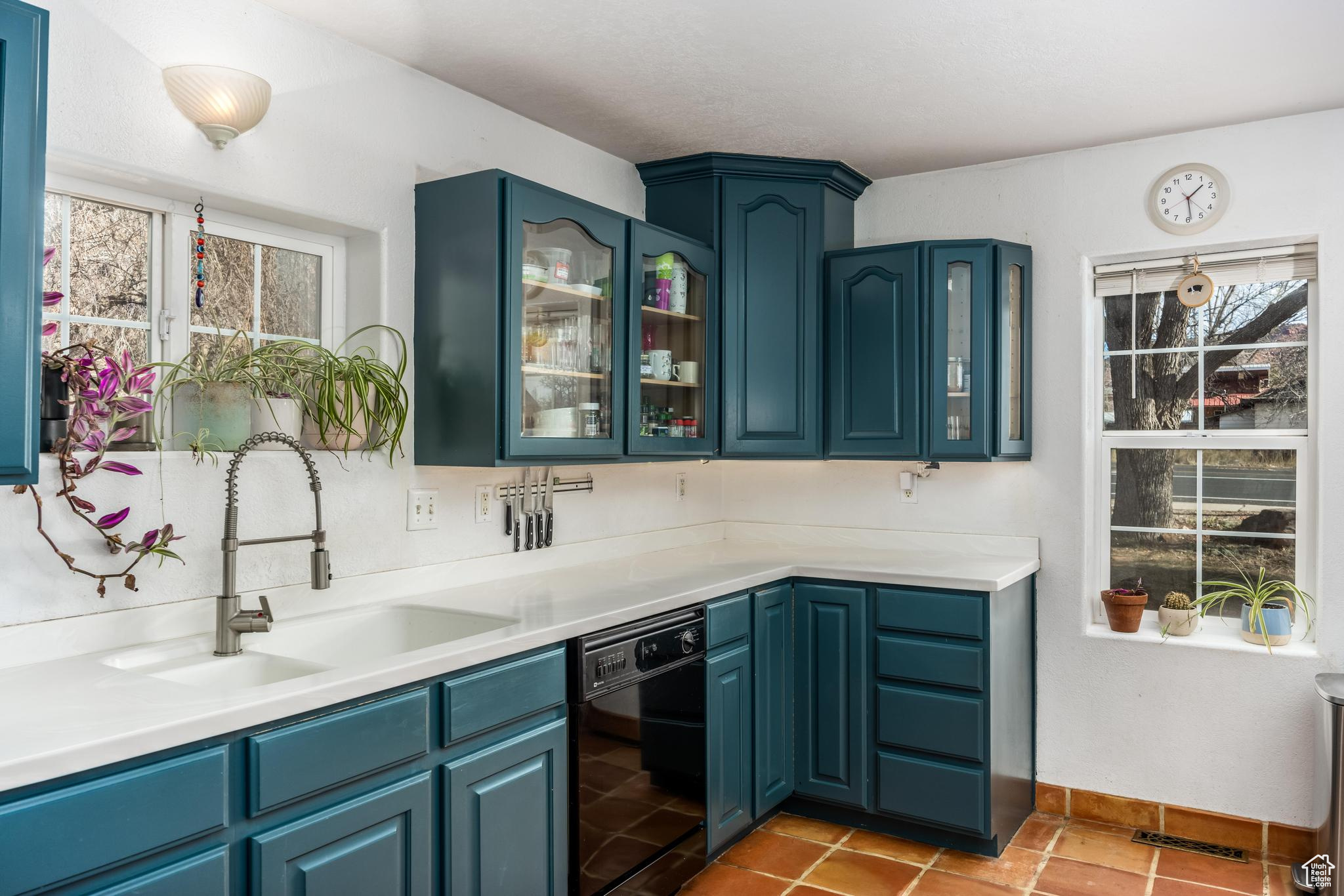 Kitchen featuring a sink, blue cabinetry, dishwasher, and a healthy amount of sunlight