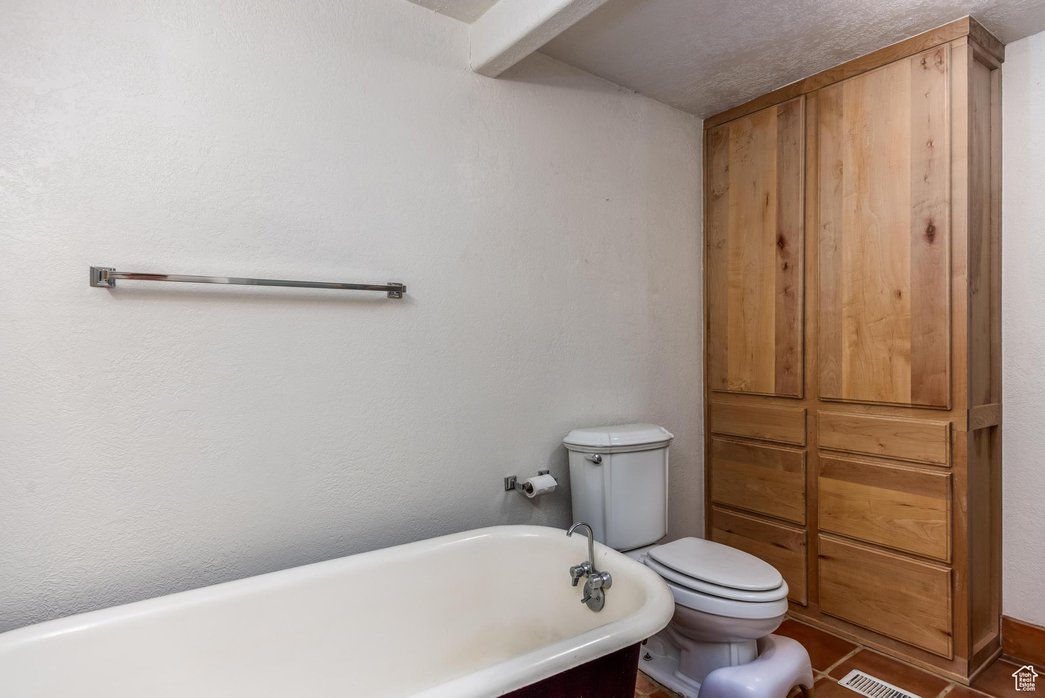 Full bathroom featuring visible vents, a freestanding bath, and toilet