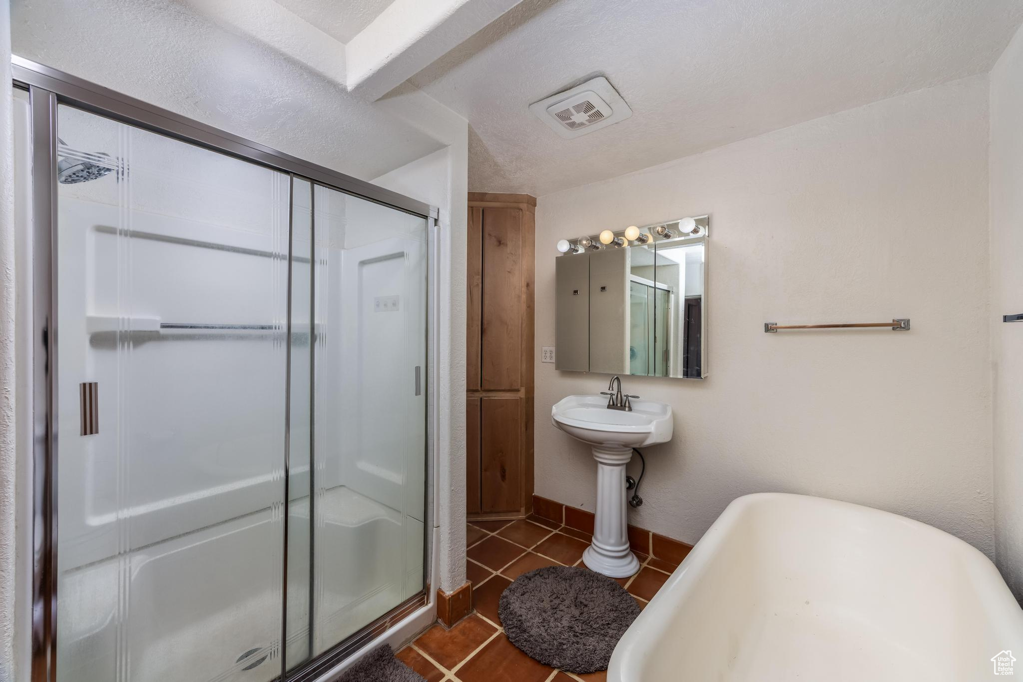 Full bathroom with baseboards, visible vents, a freestanding bath, a shower stall, and tile patterned floors