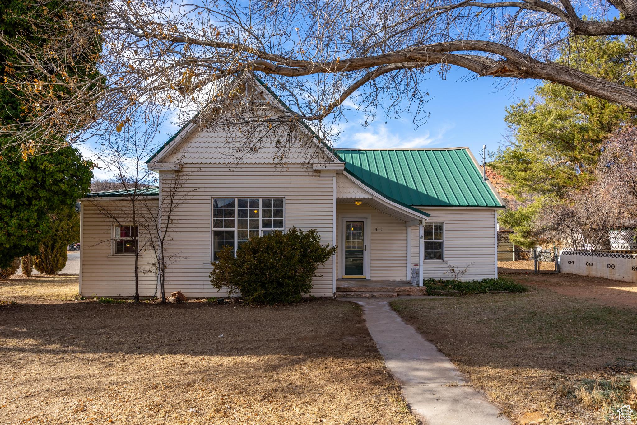 View of front of home featuring metal roof and fence