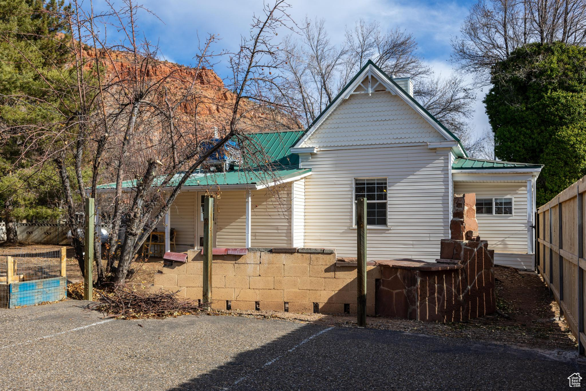 Rear view of property with a porch, metal roof, and fence