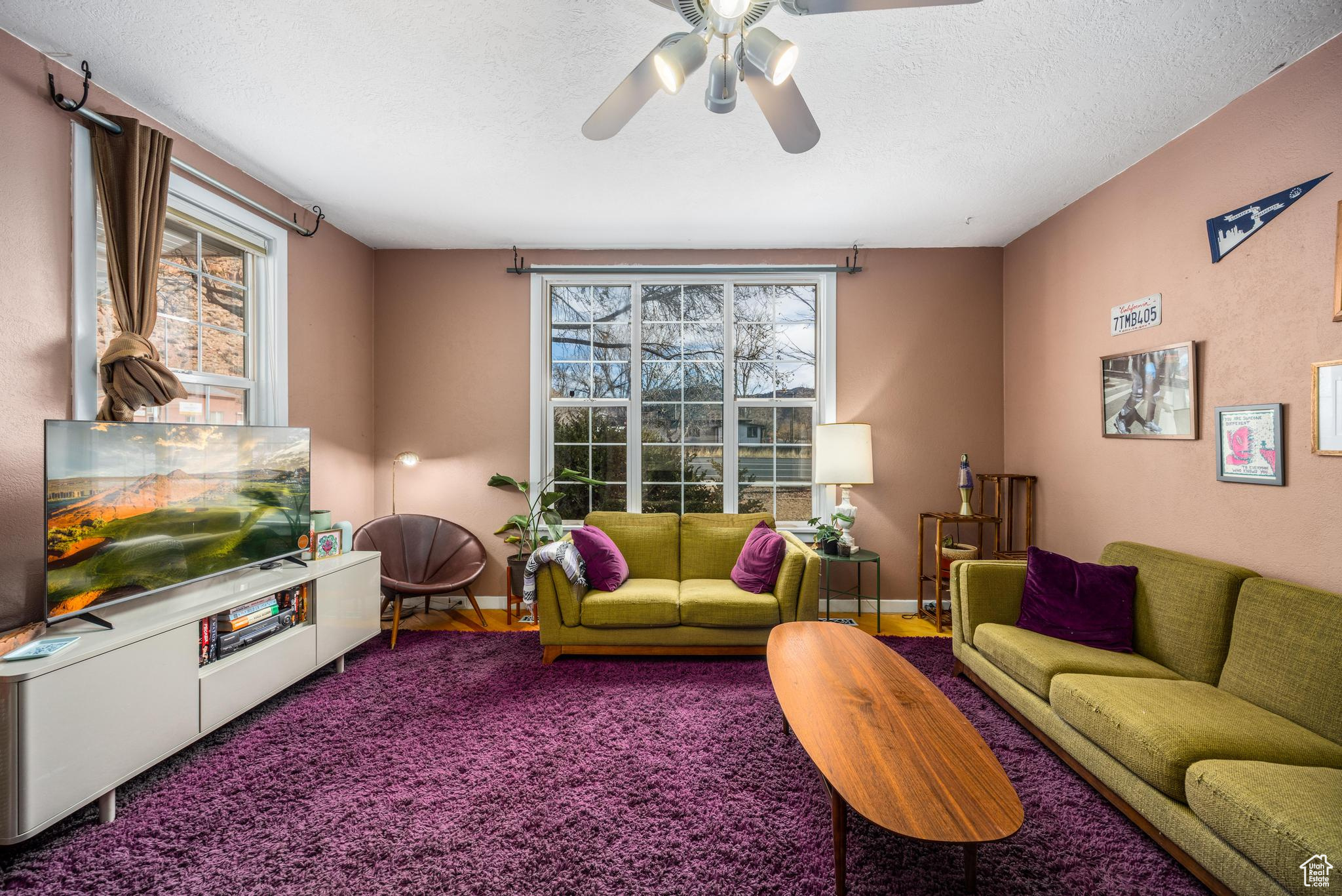 Living area featuring carpet flooring, ceiling fan, a textured ceiling, and baseboards