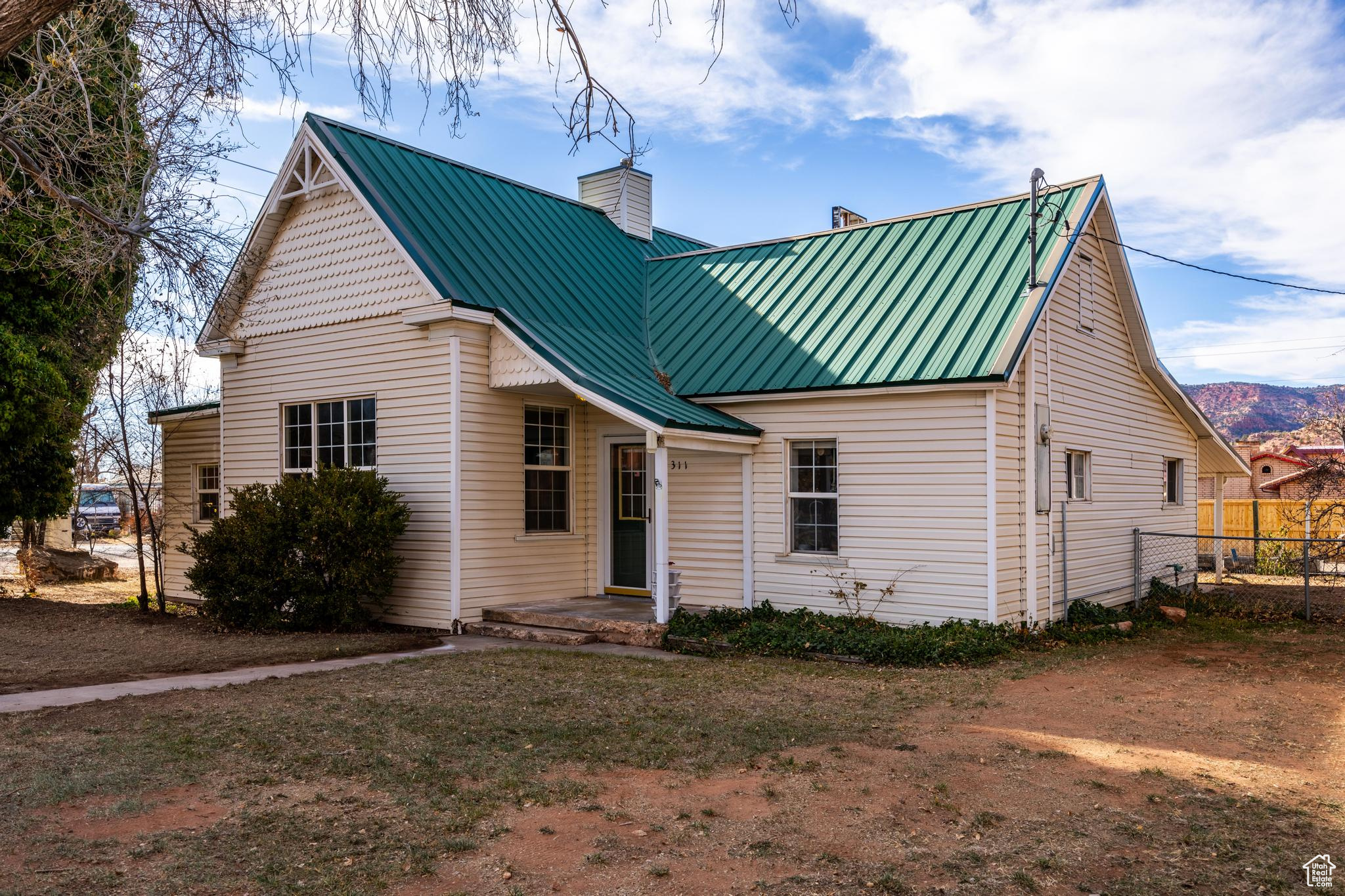 Back of house featuring metal roof, fence, and a chimney