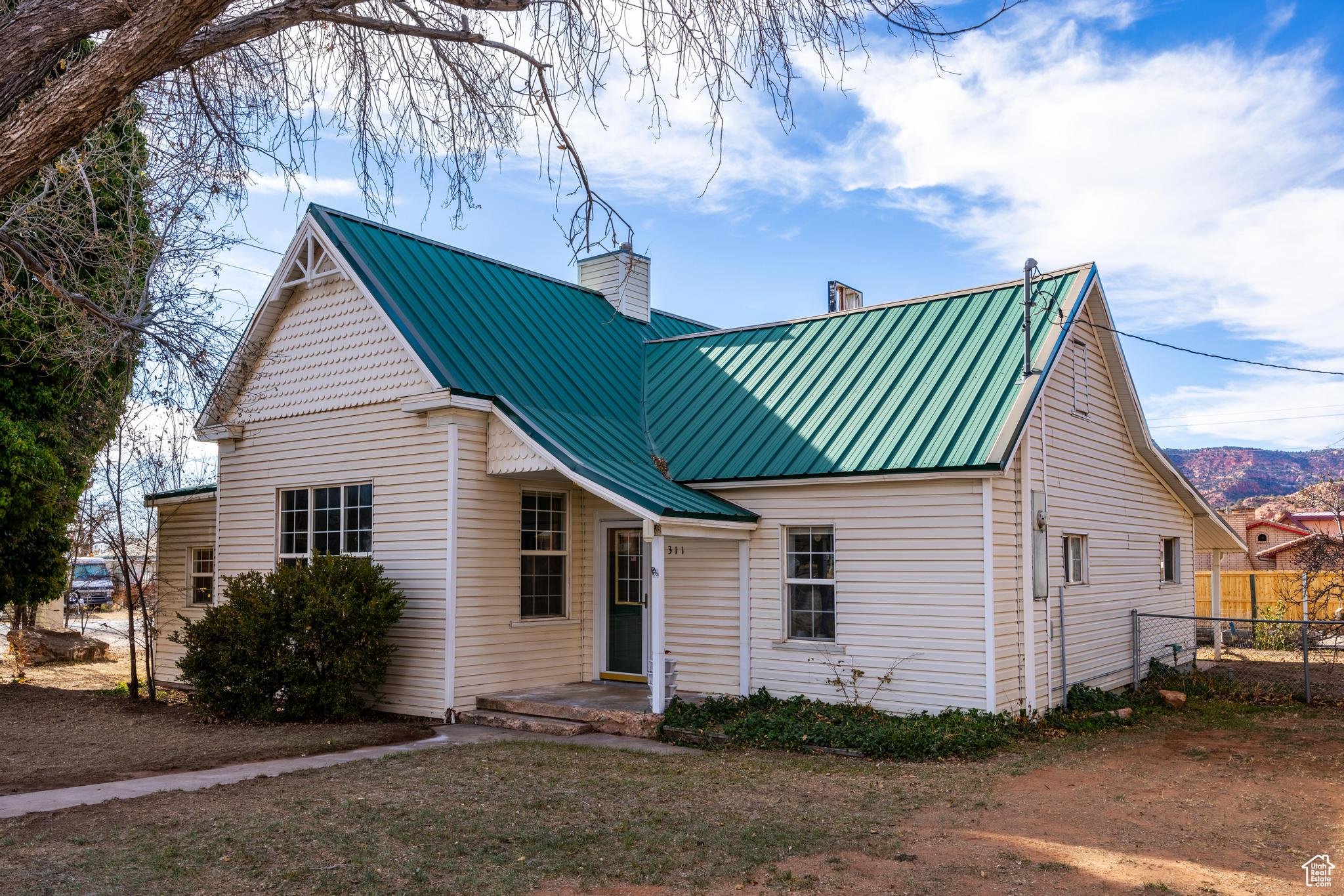 View of front of home featuring metal roof, fence, and a chimney