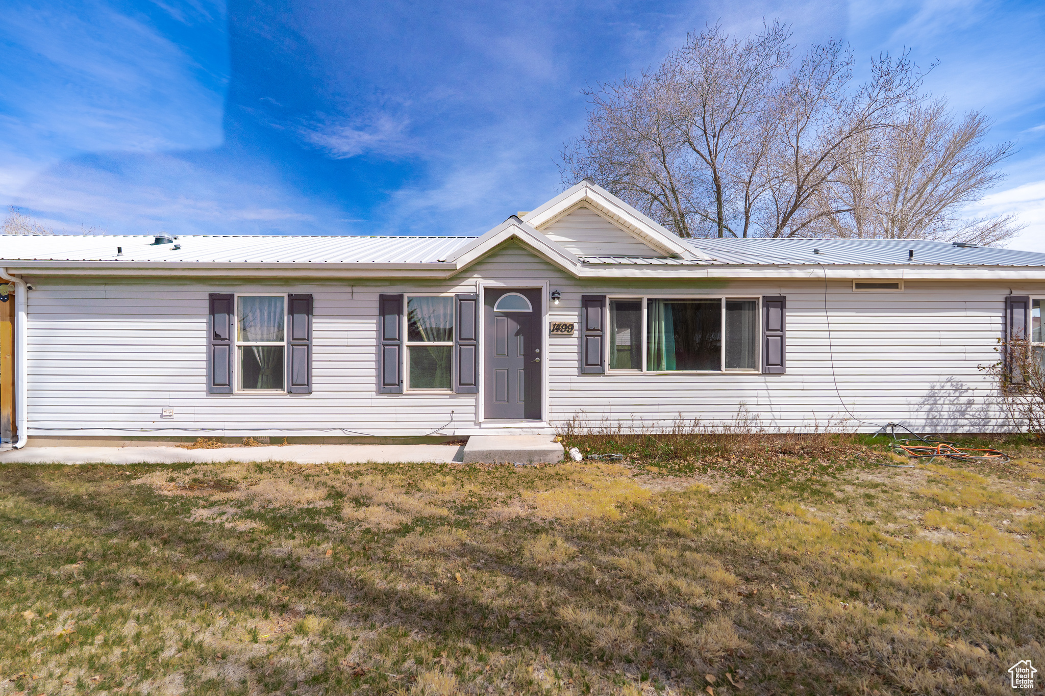 Ranch-style house with a front yard and metal roof