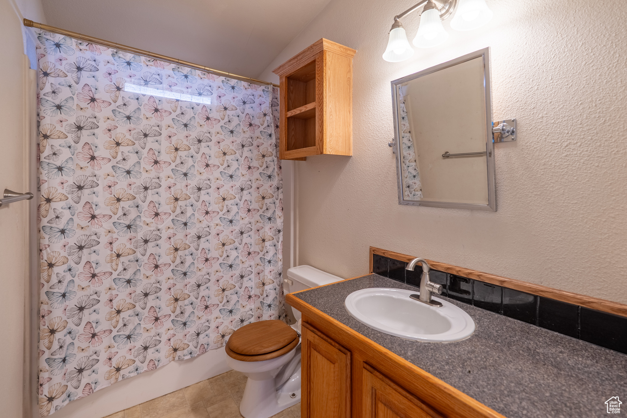 Bathroom with a textured wall, vanity, and toilet