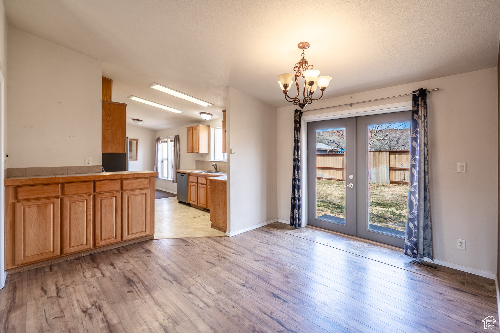 Kitchen featuring light wood-style floors, french doors, plenty of natural light, and stainless steel dishwasher