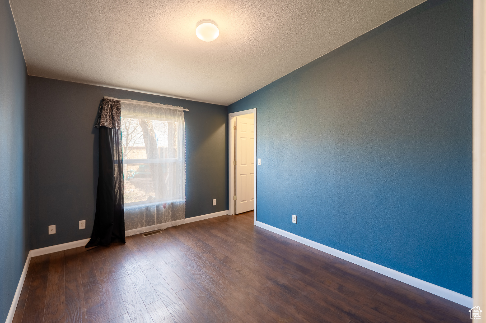 Spare room with visible vents, baseboards, vaulted ceiling, and wood finished floors