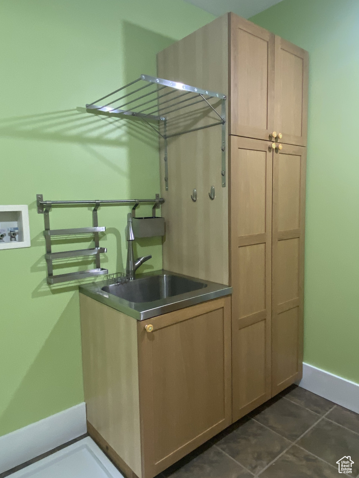 Clothes washing area featuring washer hookup, dark tile patterned floors, a sink, cabinet space, and baseboards