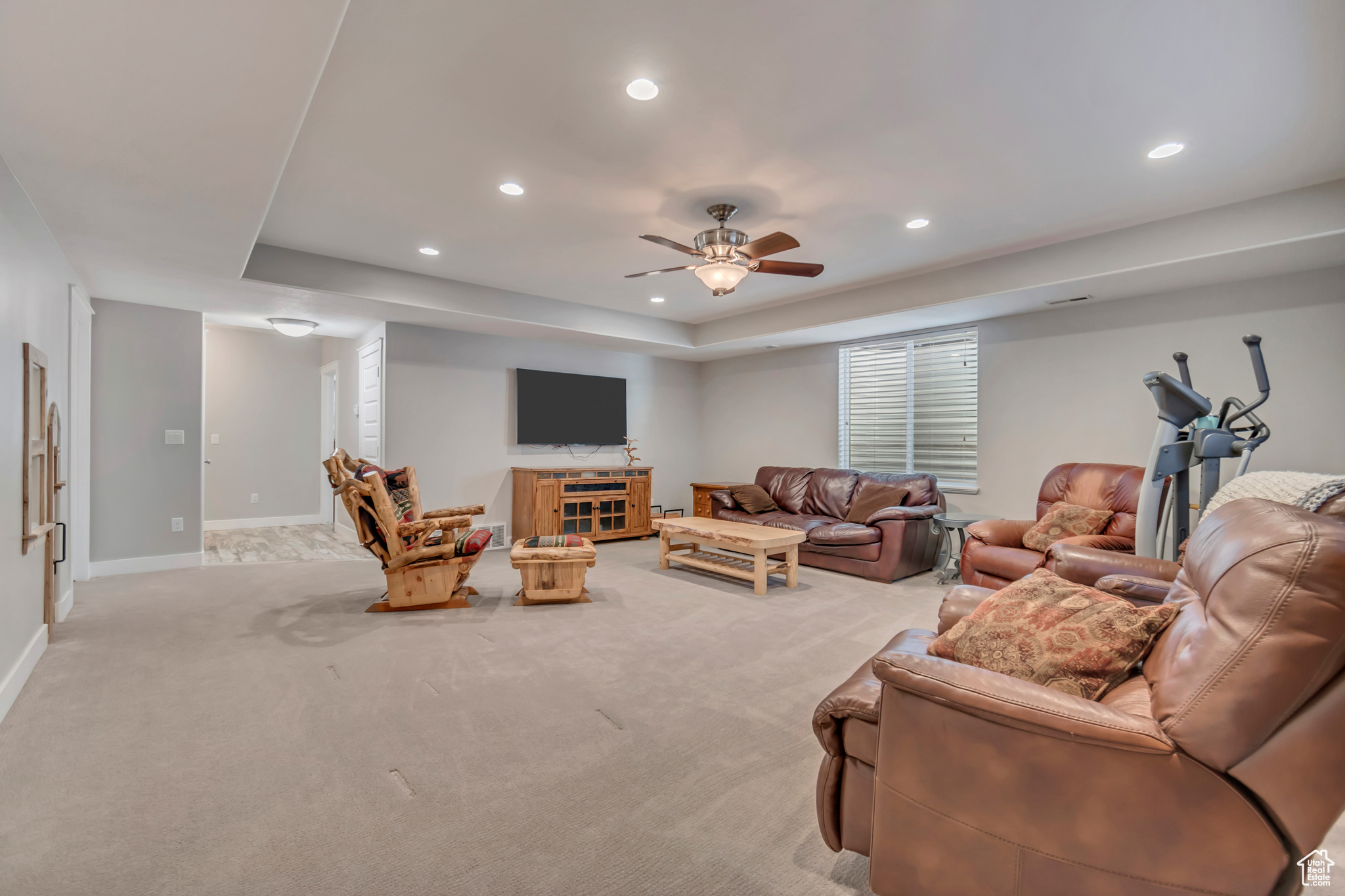 Living area with a tray ceiling, a ceiling fan, recessed lighting, carpet