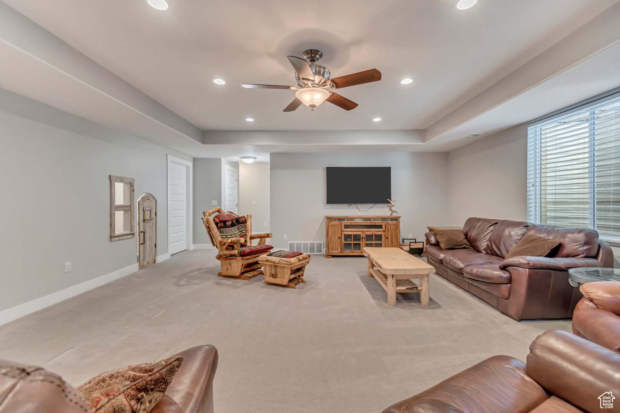 Living area with a tray ceiling, a ceiling fan, recessed lighting, carpet