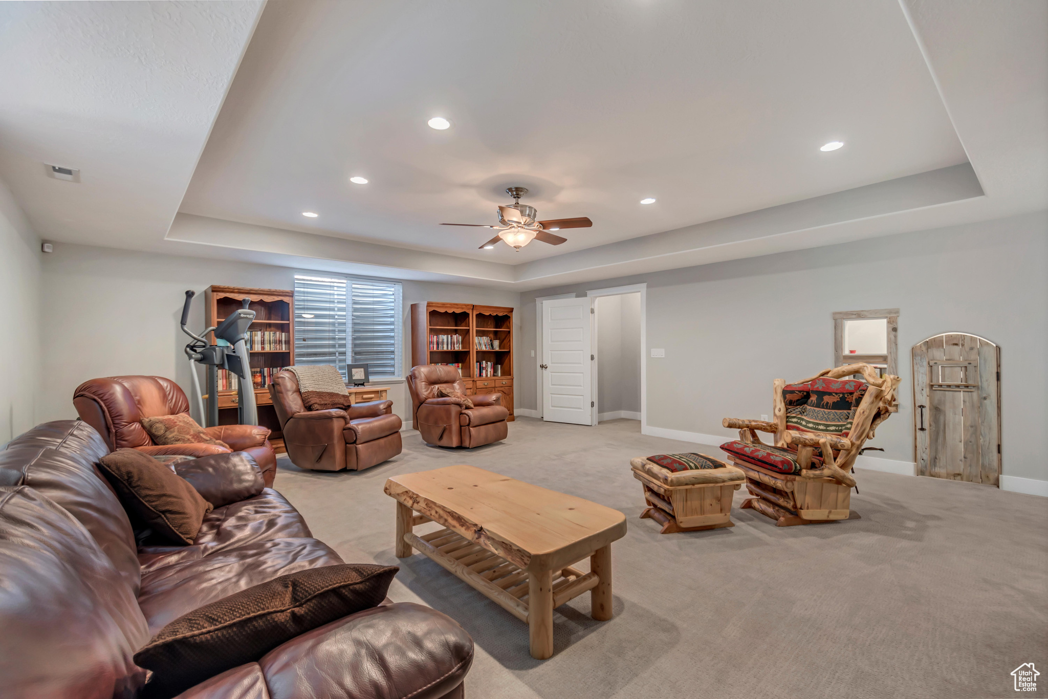 Living area with a tray ceiling, a ceiling fan, recessed lighting, carpet