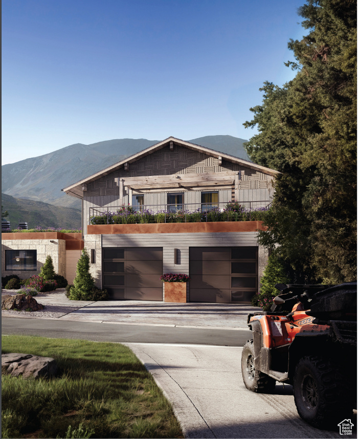 View of front of property with a mountain view, a garage, driveway, and a balcony