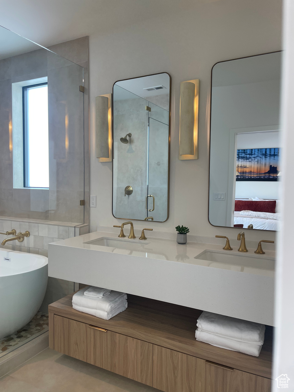 Bathroom with ensuite bath, a shower stall, double vanity, and a sink