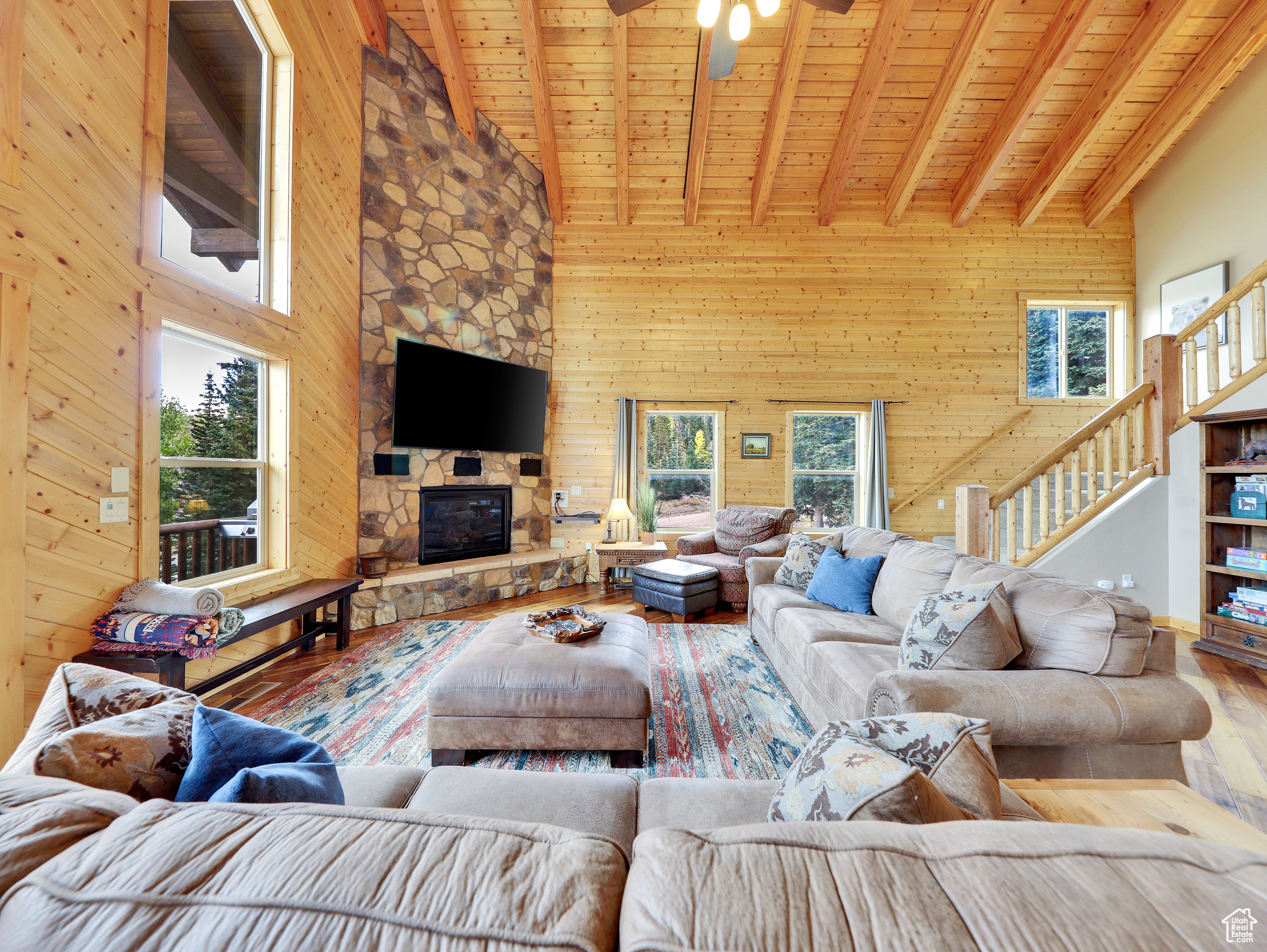 Living area featuring beam ceiling, wood finished floors, wooden walls, wooden ceiling, and a fireplace