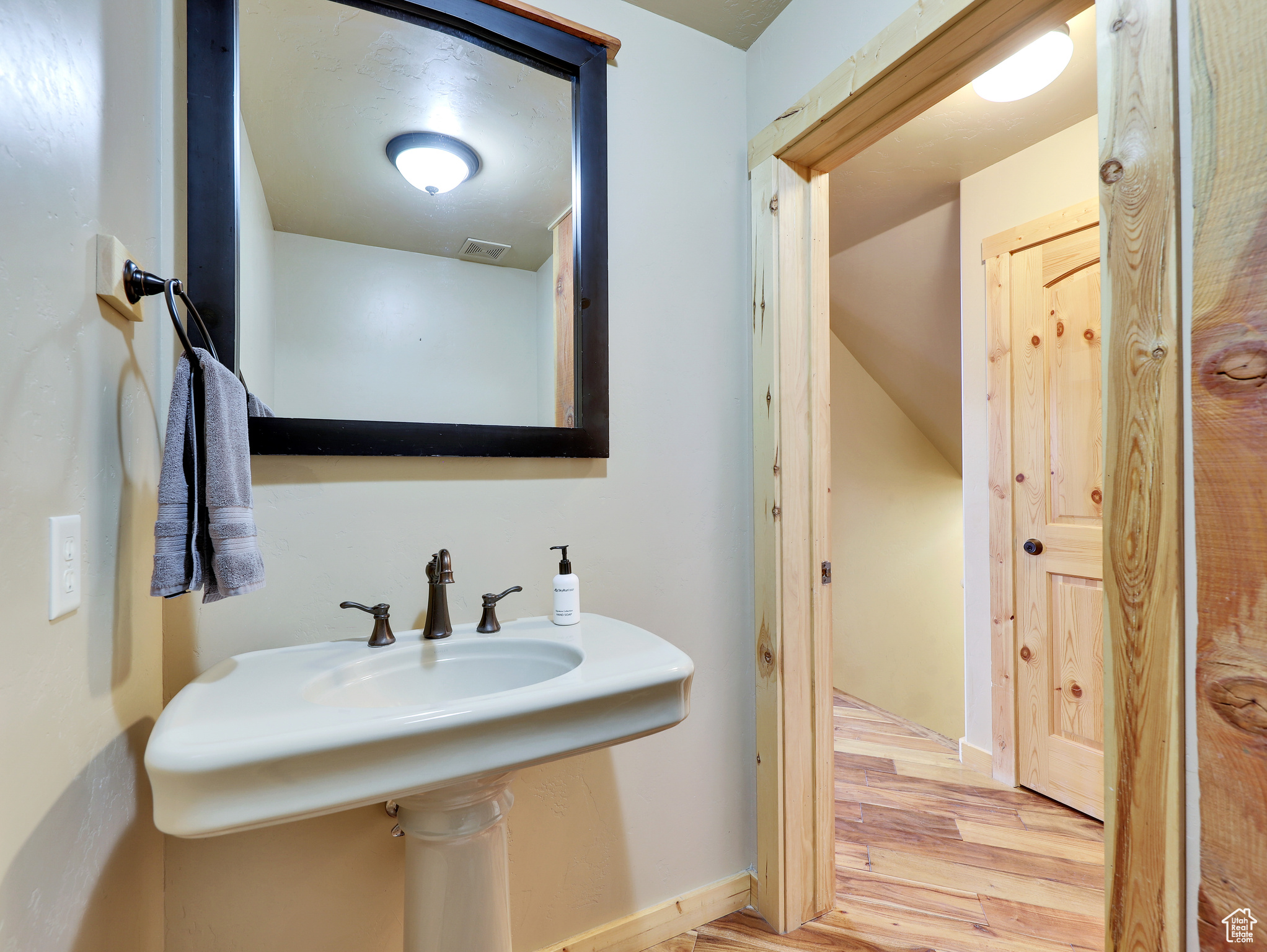 Bathroom with visible vents, a sink, baseboards, and wood finished floors