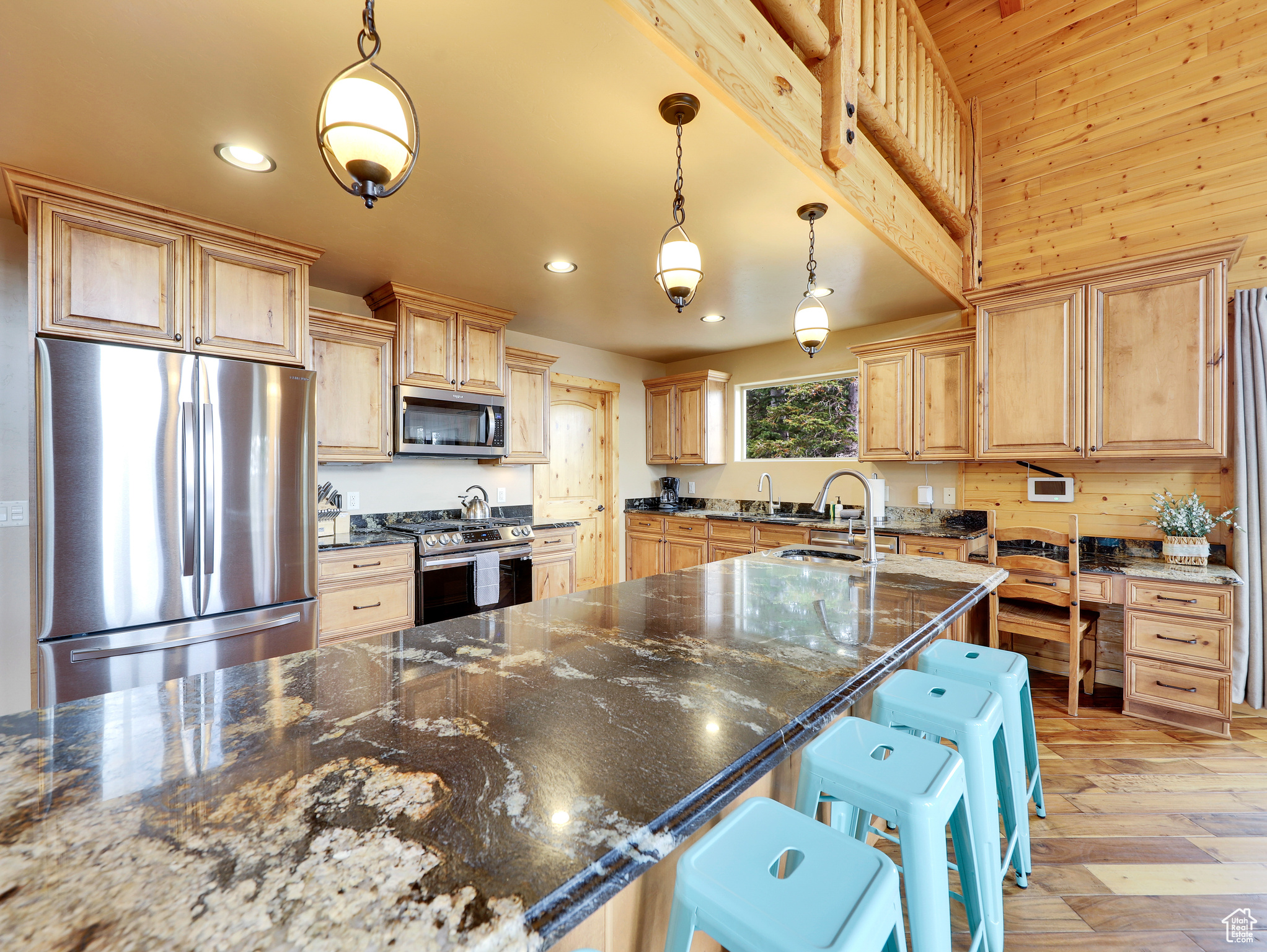 Kitchen with light brown cabinets, appliances with stainless steel finishes, light wood-type flooring, and a sink