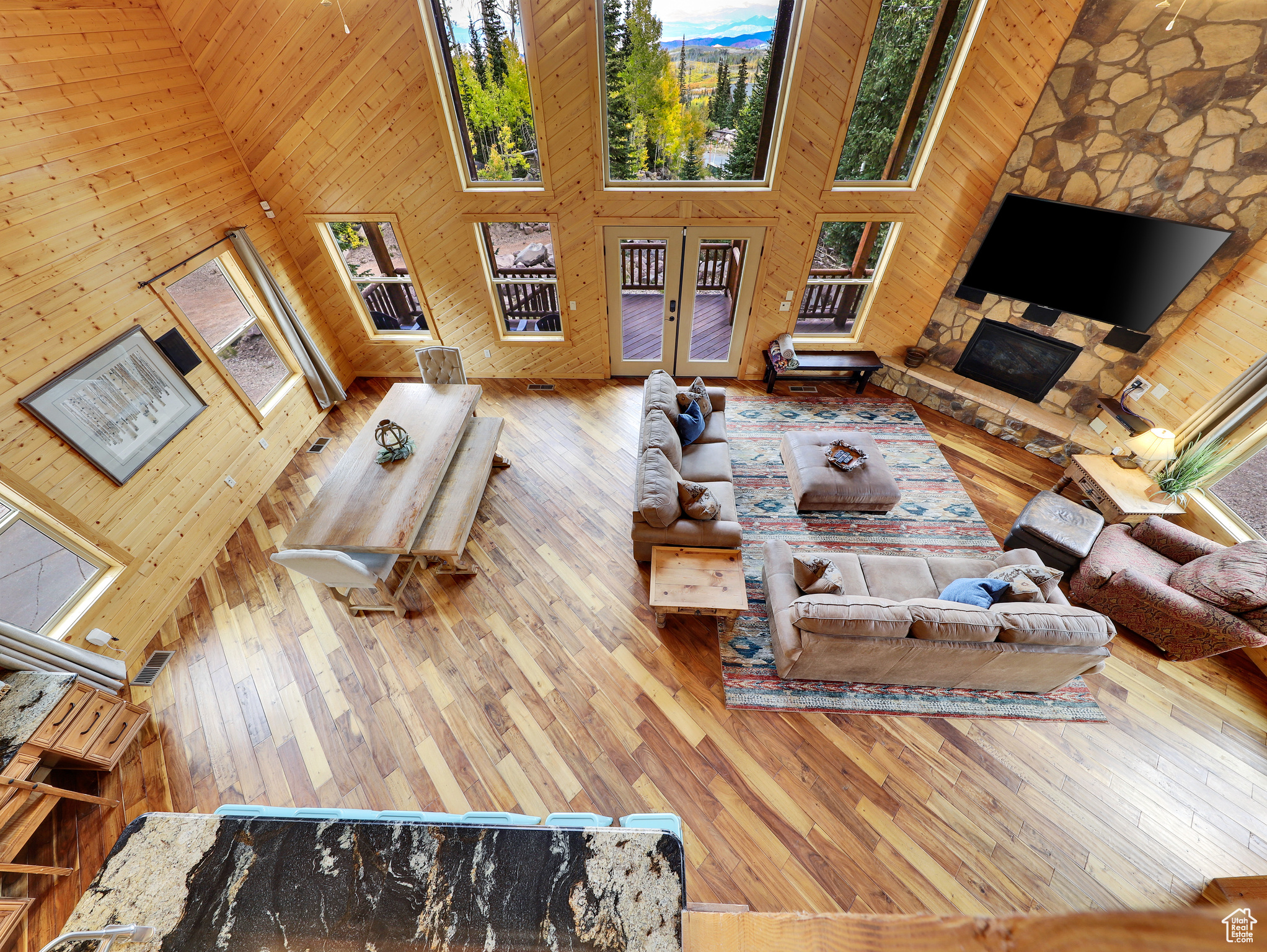 Living area featuring wood walls, french doors, high vaulted ceiling, and wood-type flooring