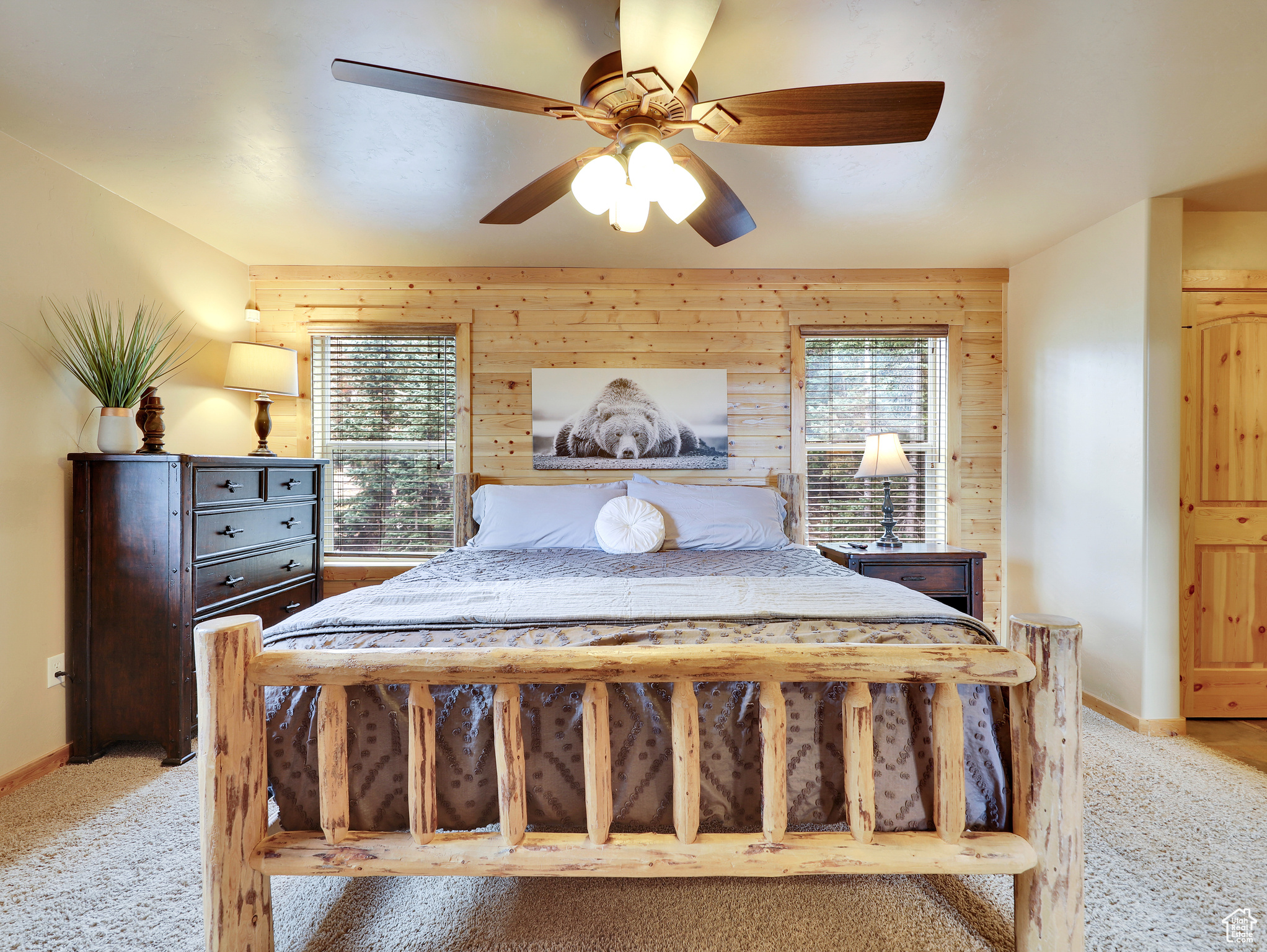 Bedroom with a ceiling fan, wooden walls, light colored carpet, and baseboards