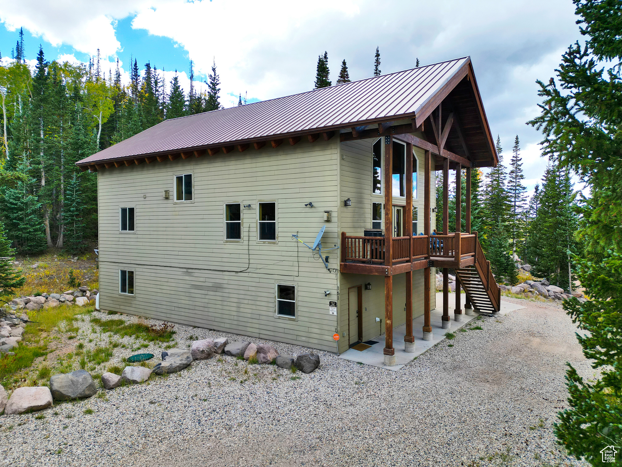 Rear view of house featuring metal roof, a wooden deck, stairs, and a standing seam roof