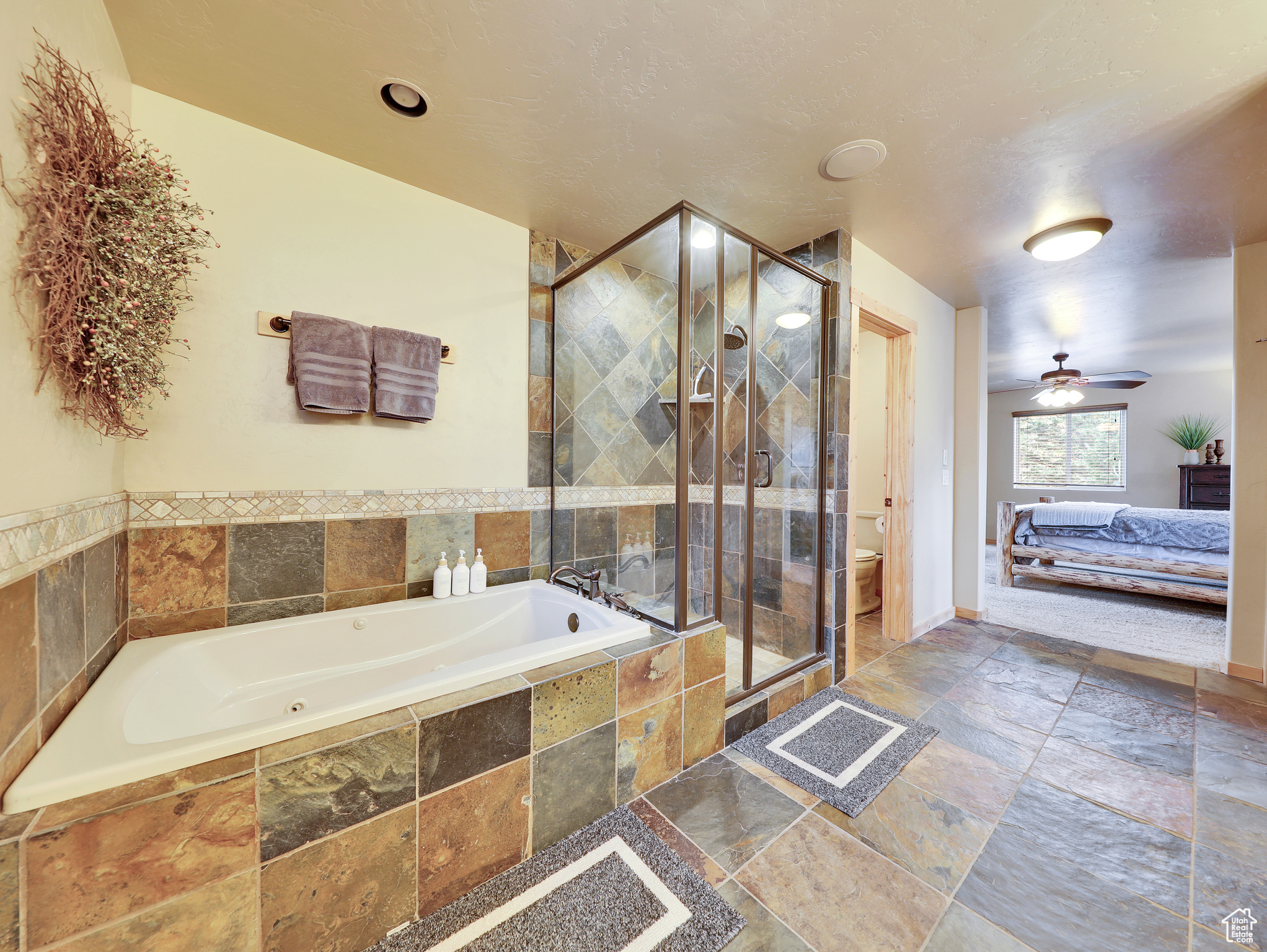 Ensuite bathroom with a garden tub, toilet, a stall shower, stone tile flooring, and ensuite bath