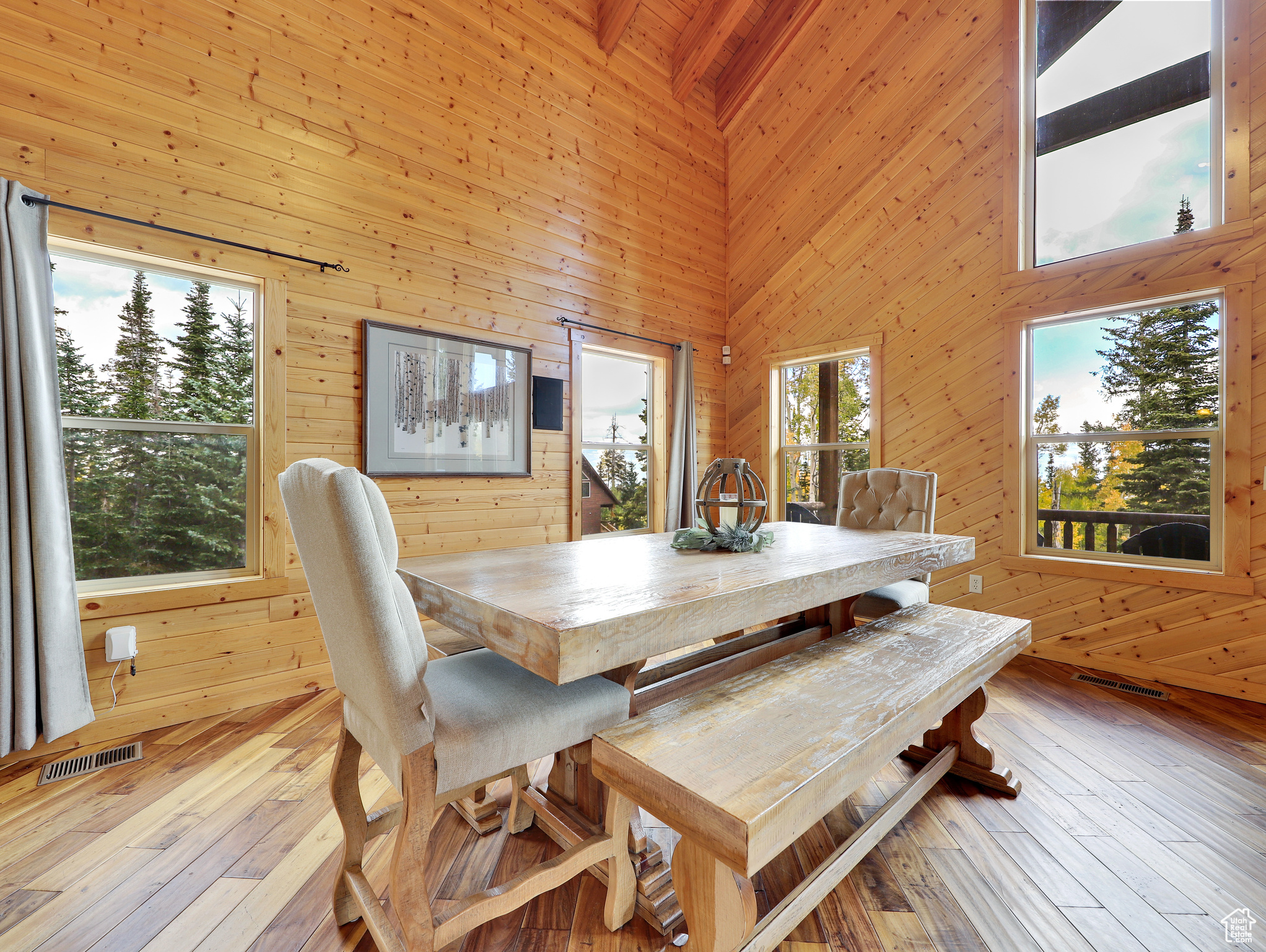 Dining area featuring visible vents, wood walls, a high ceiling, and wood-type flooring