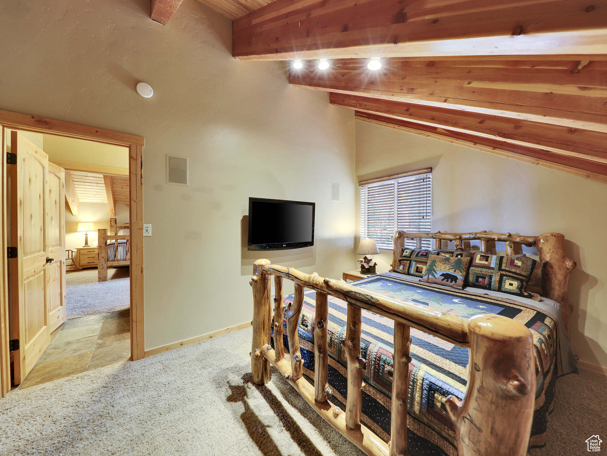 Bedroom featuring carpet flooring, visible vents, lofted ceiling with beams, and baseboards