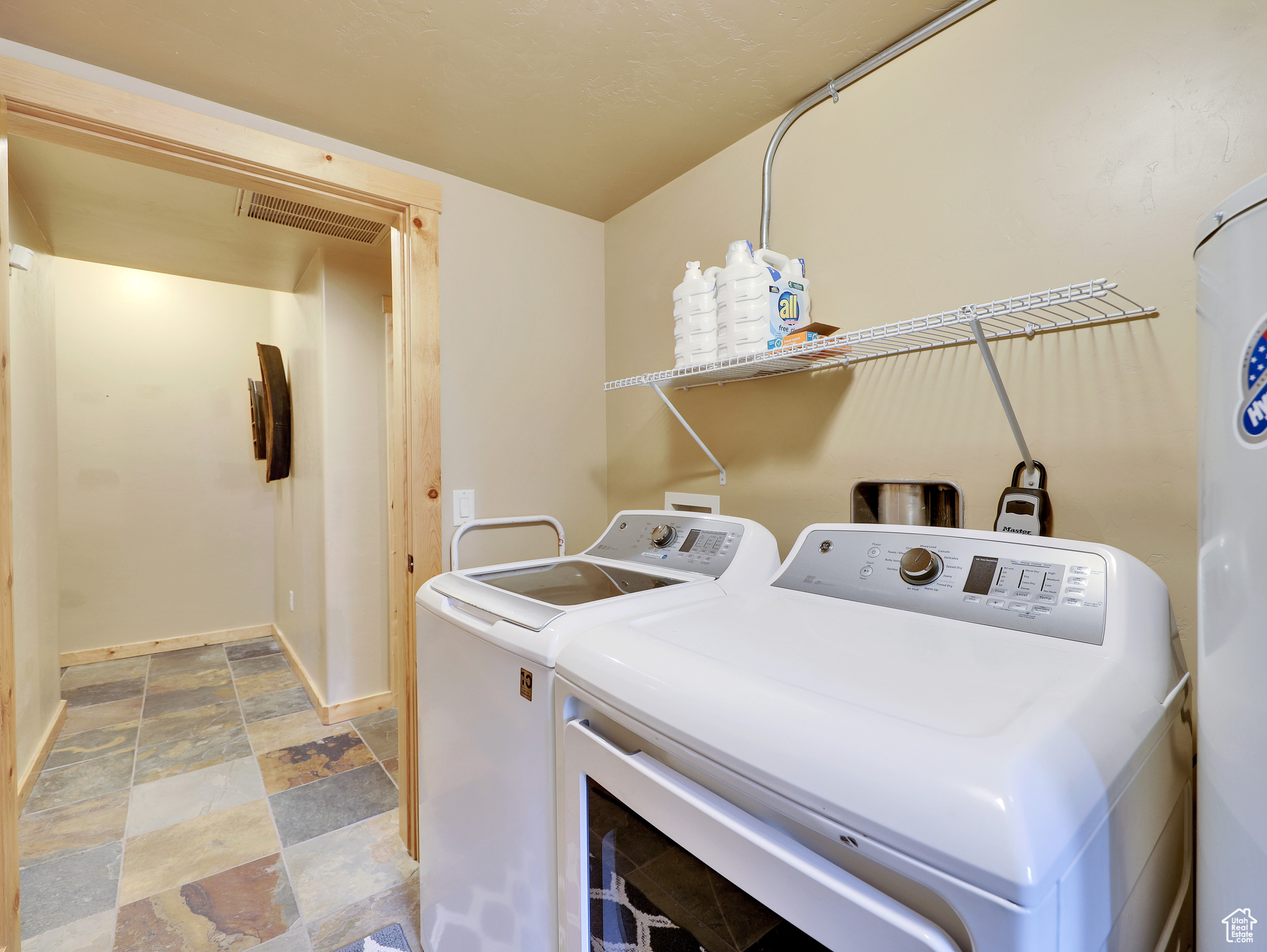 Laundry area featuring baseboards, visible vents, laundry area, stone finish flooring, and washing machine and dryer